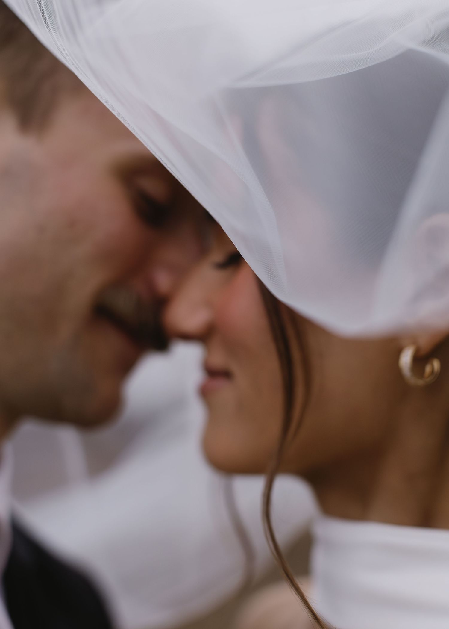 Romantic close-up shot of couple under wedding veil sharing intimate moment.