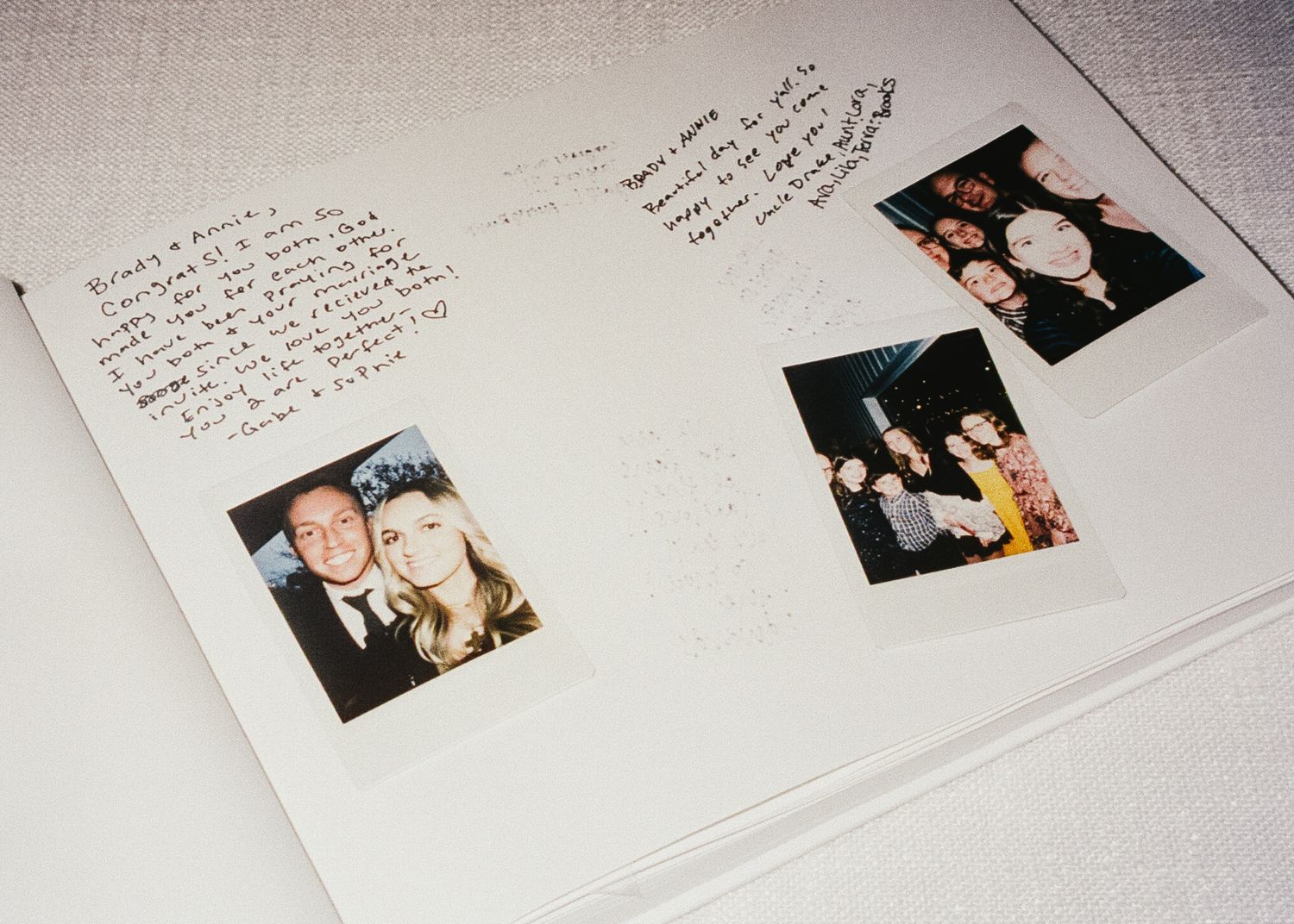 Wedding guest book with handwritten messages and photos spread across white pages.