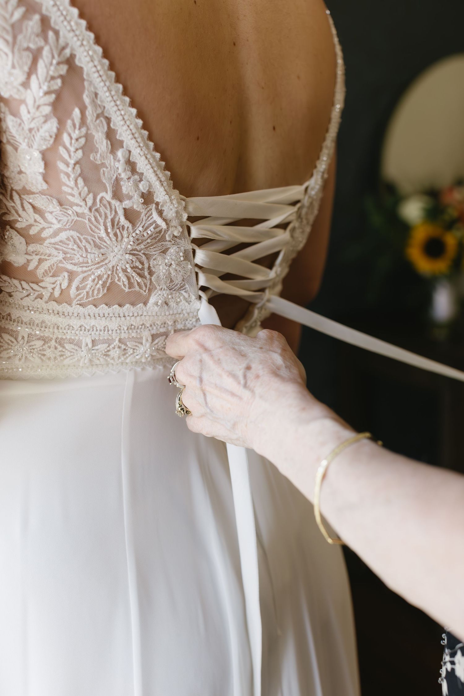 Close-up of lacing detail on the back of an elegant white wedding dress with delicate lace embellishments.