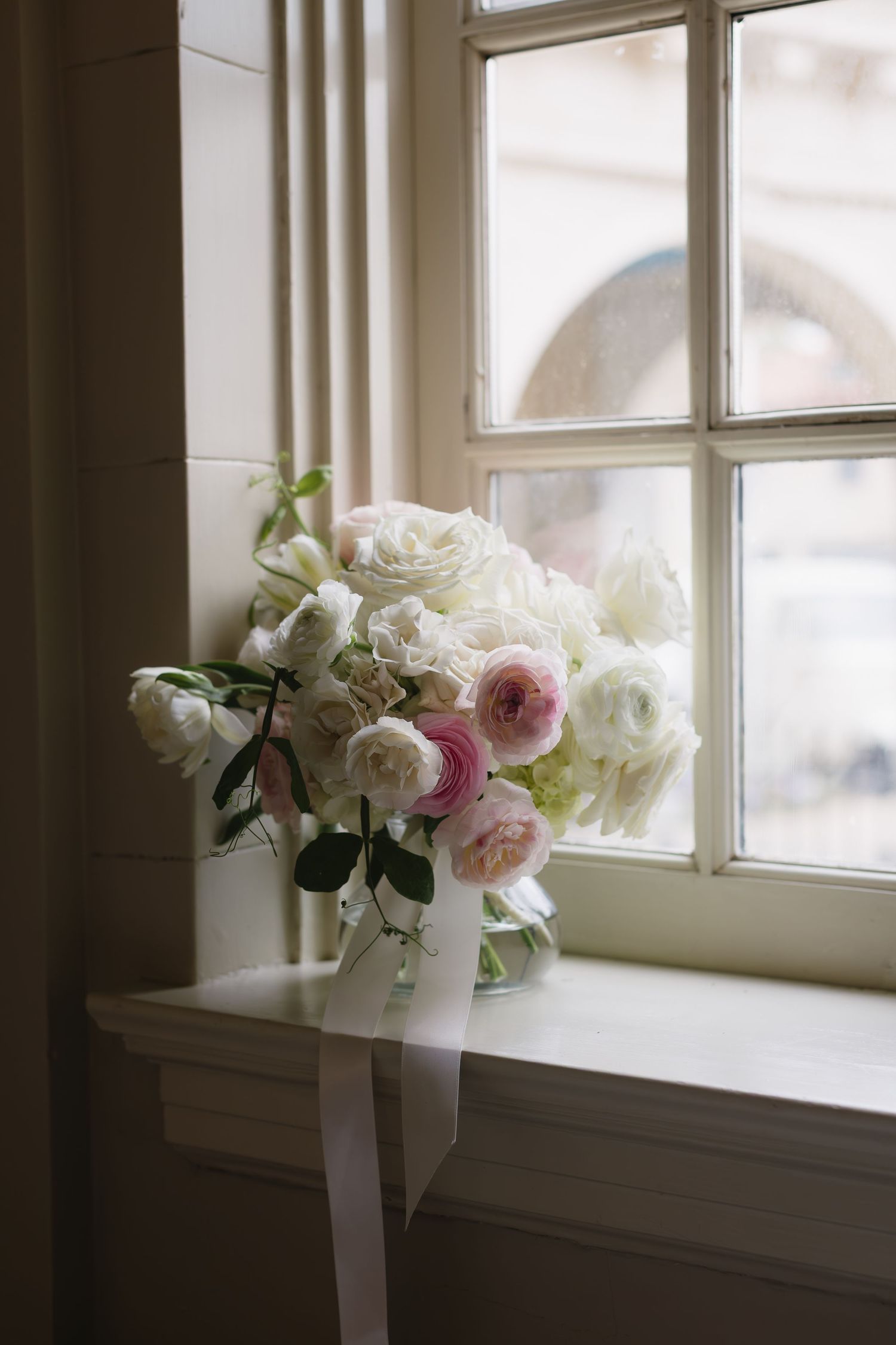 A series of delicate pink and white roses in a vase by a window, shown in multiple soft-focus frames.