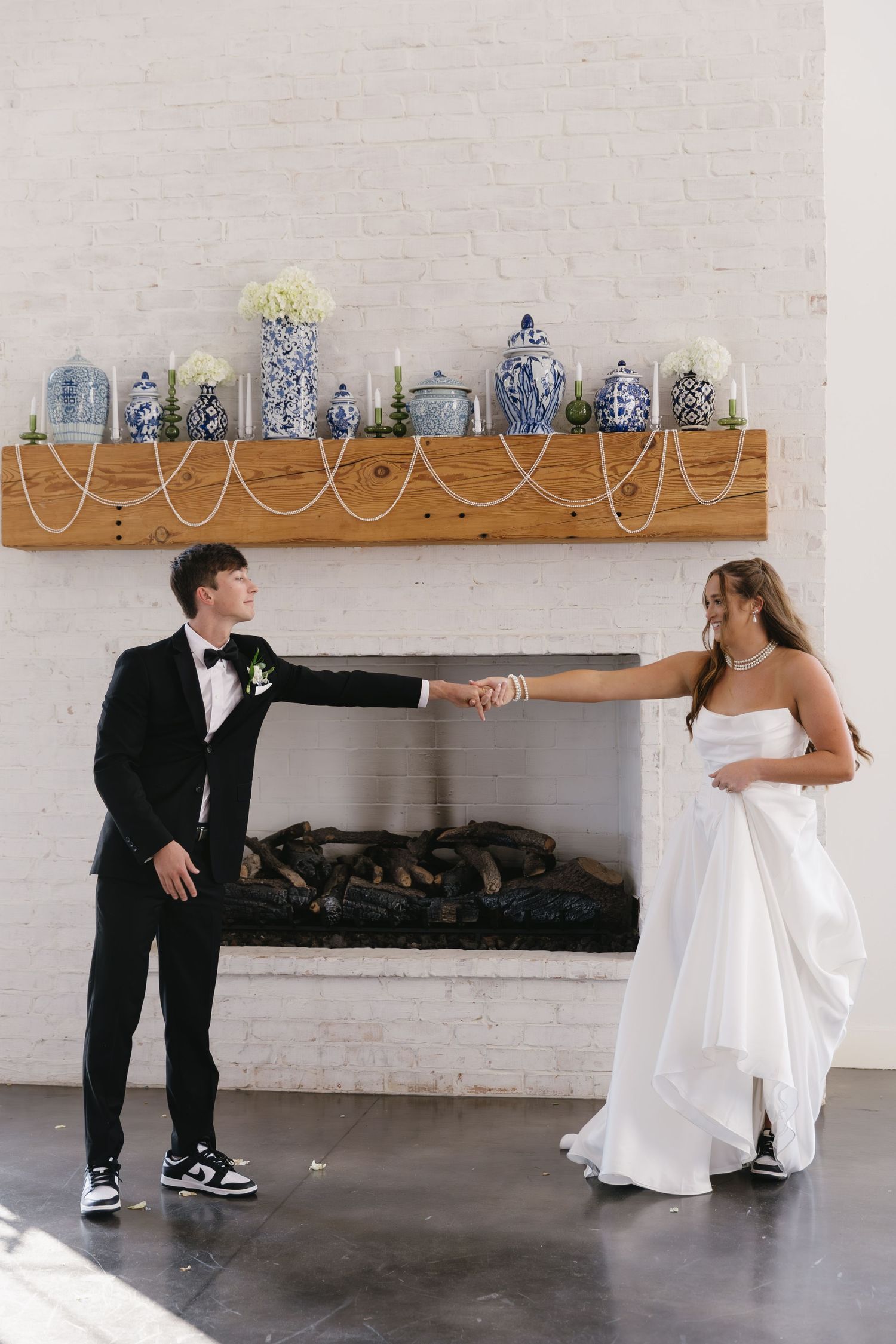 Playful wedding photos taken in a modern indoor venue with white brick walls.