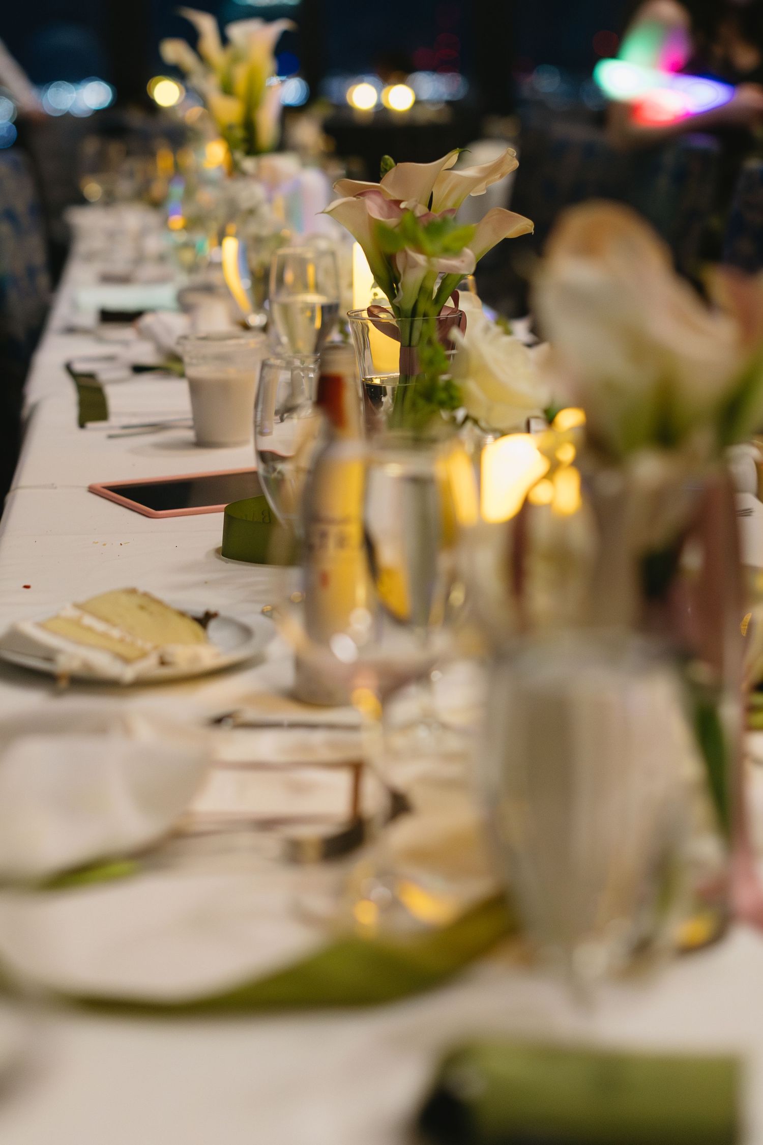 Elegant wedding reception table settings with white linens and soft lighting create an intimate atmosphere.
