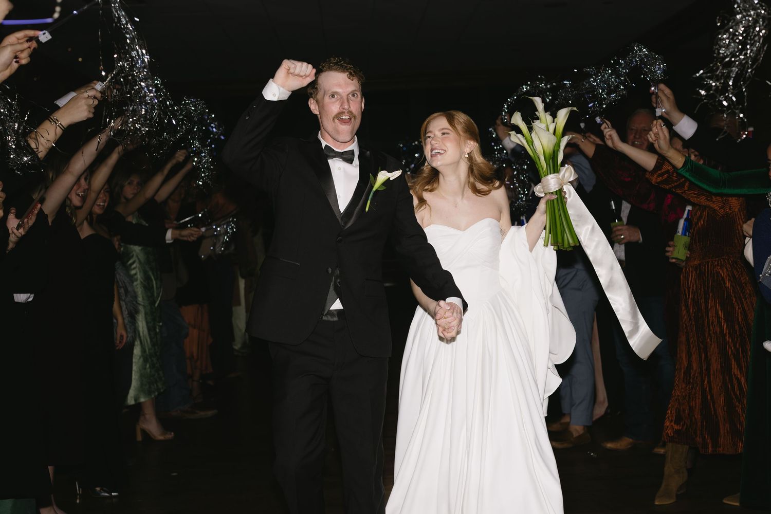 Wedding couple celebrating with guests under sparkling lights.