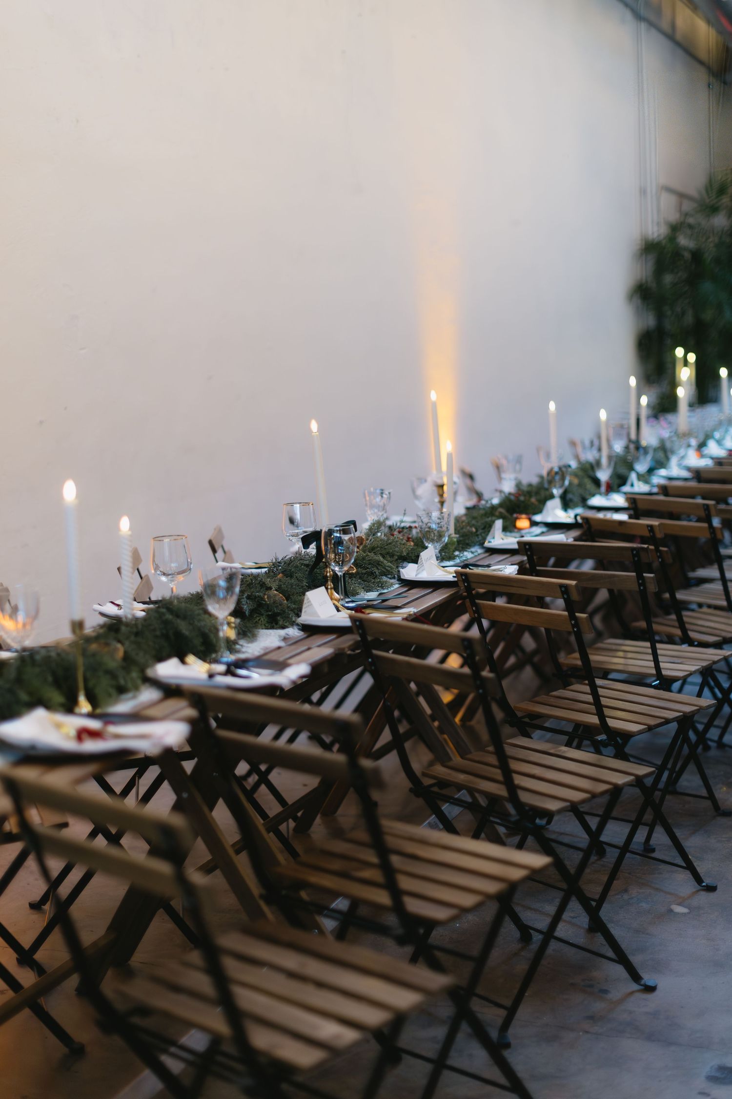 Wooden picnic tables arranged in rows with lit candles creating an intimate outdoor dining atmosphere.