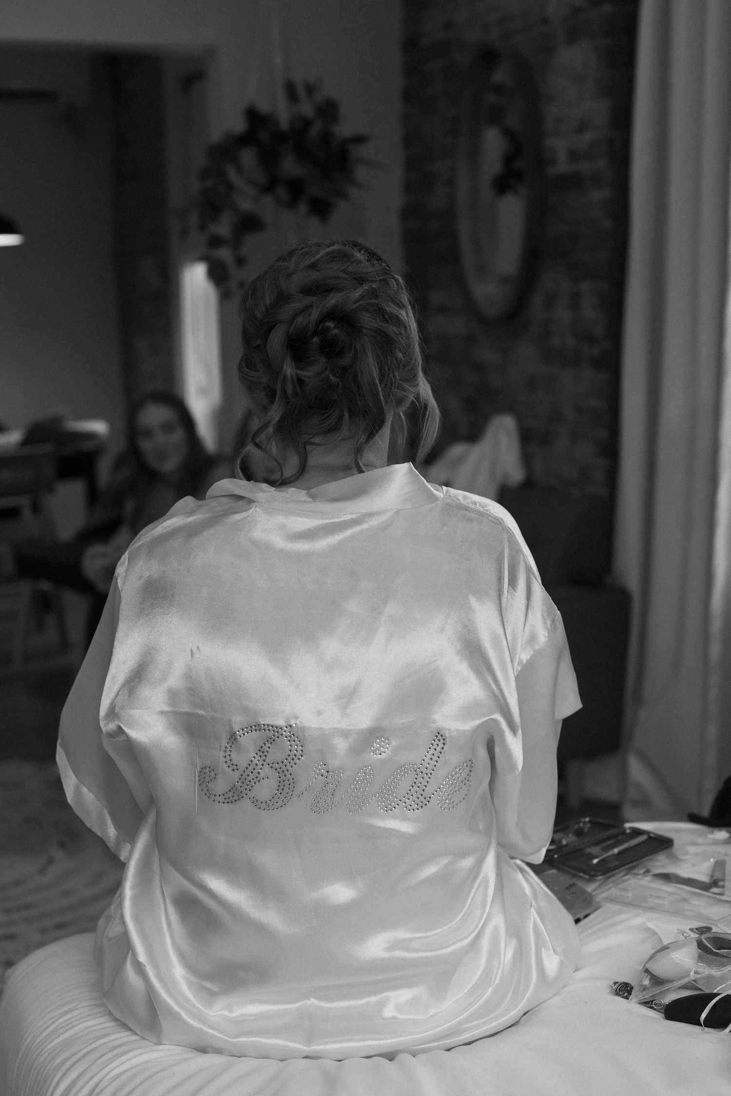 Several white satin wedding dresses displayed on hangers against a dark background.