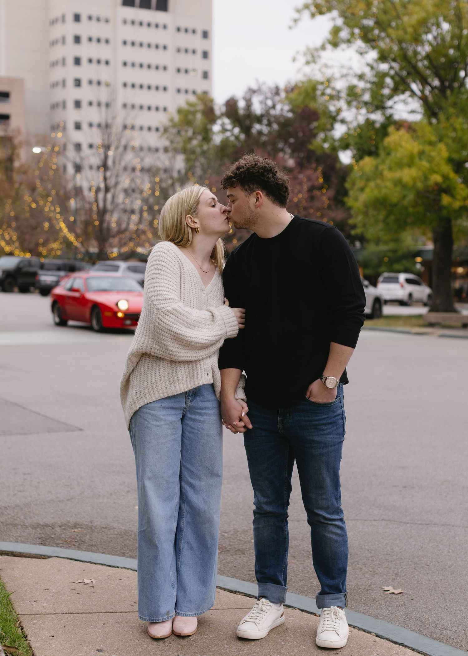 A romantic moment between a couple on an urban sidewalk wearing matching light and dark sweaters.
