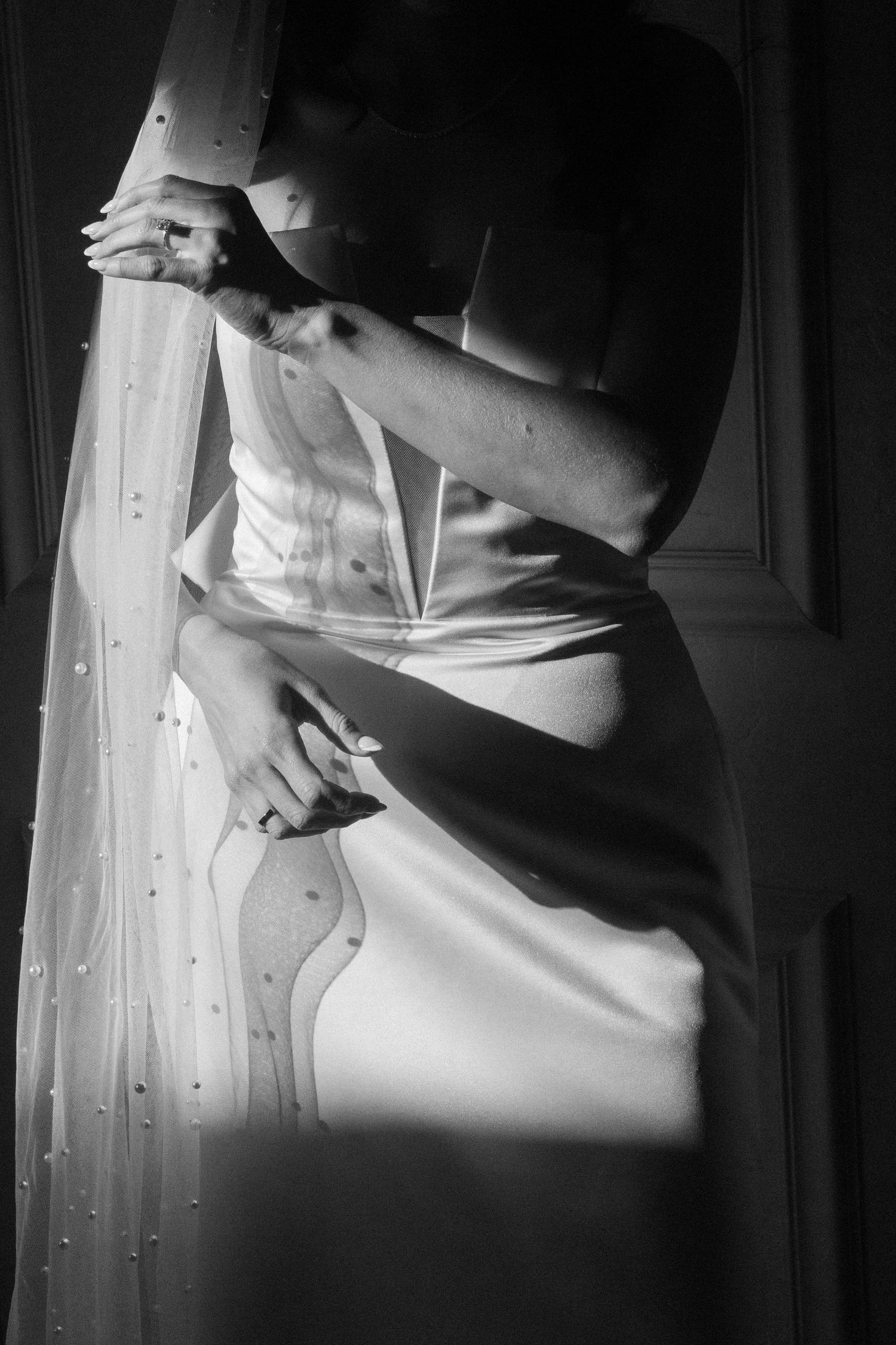 Artistic black and white detail shot of wedding dress fabric and veil.