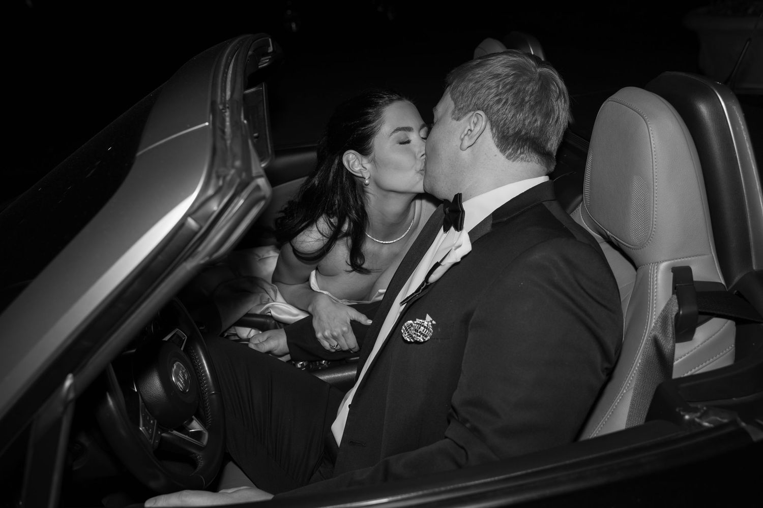 A romantic moment captured in a car at night during a wedding celebration.