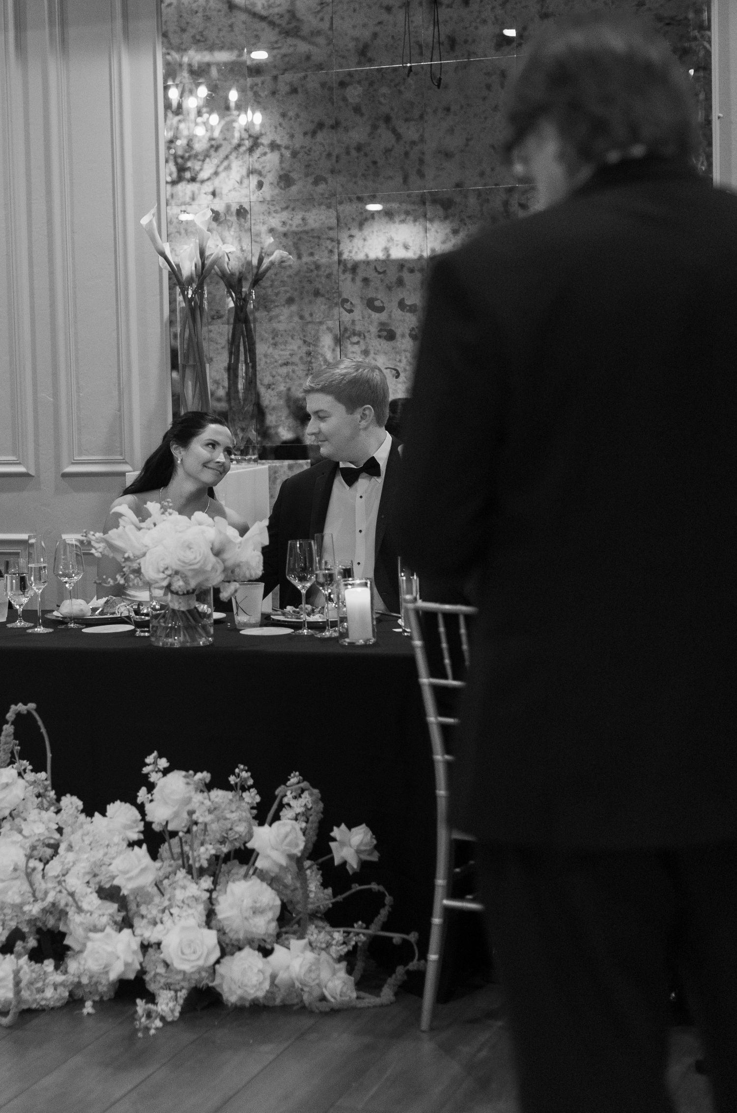Wedding reception table decorated with abundant white floral arrangements.
