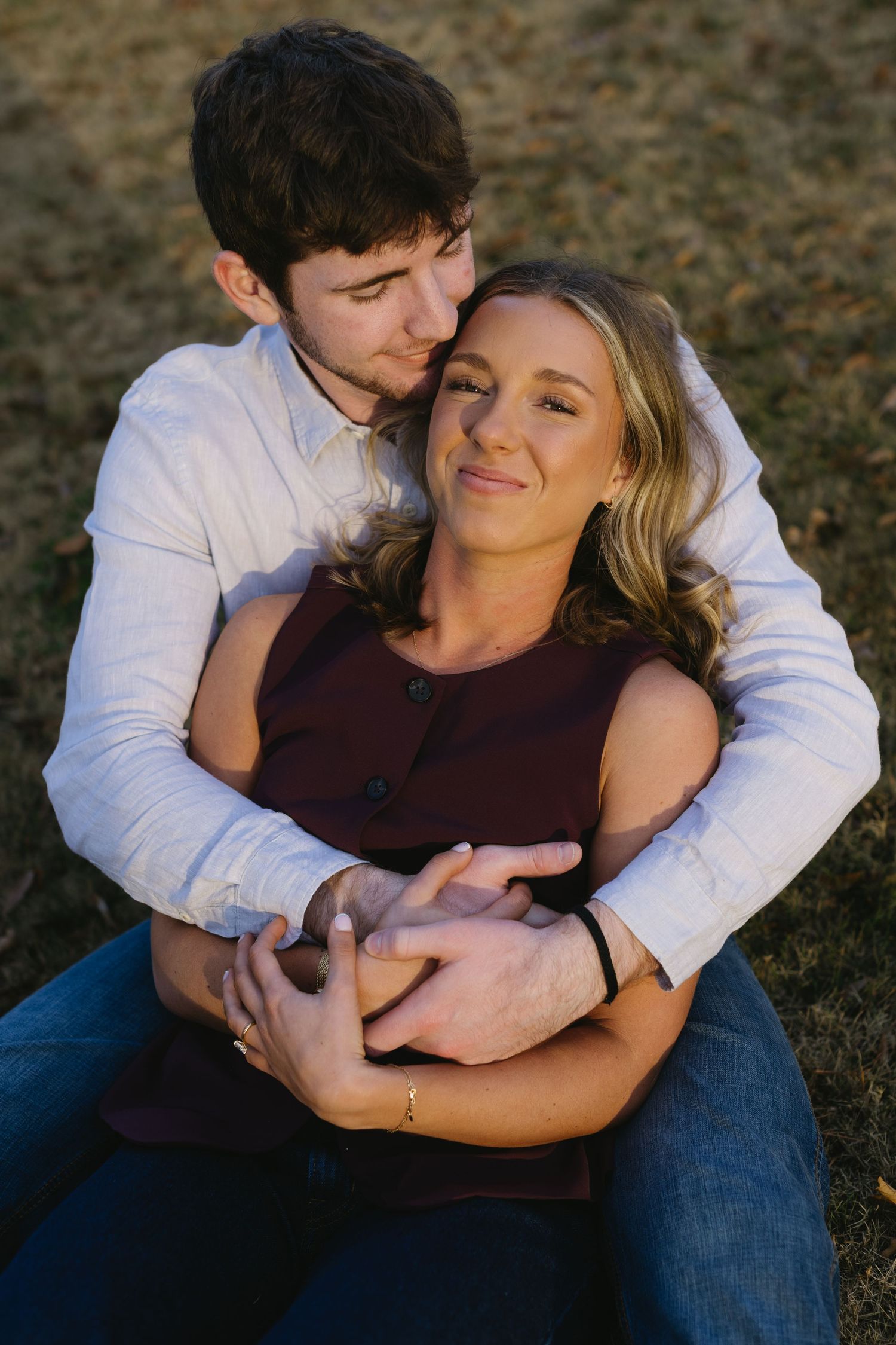 A couple shares tender embraces while sitting together outdoors during an intimate photo session.