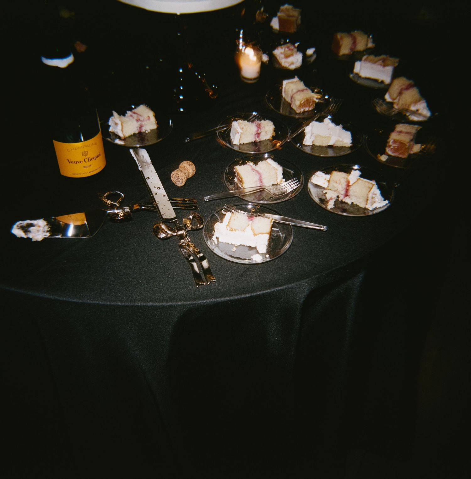 Wedding reception aftermath showing used plates and decorations on a dark tablecloth.