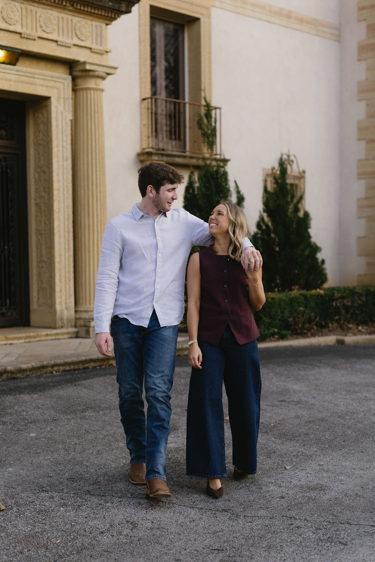 Couple walking together and smiling outside a classical building with columns.