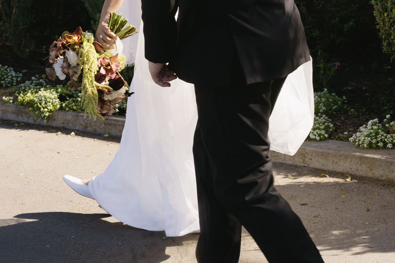 Wedding couple posing together on garden pathway.