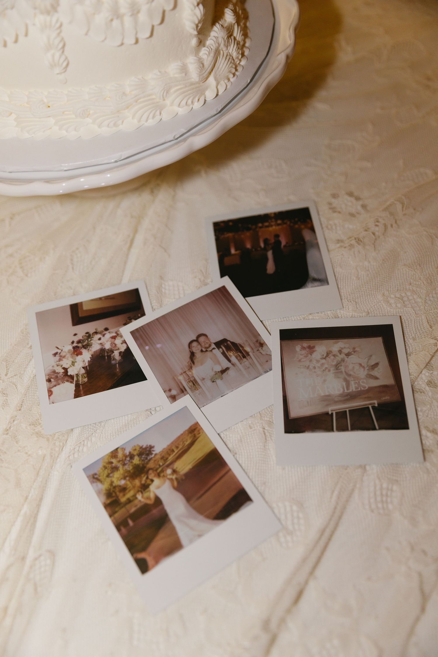 Wedding photographs scattered on white textured tablecloth in vintage style arrangement.