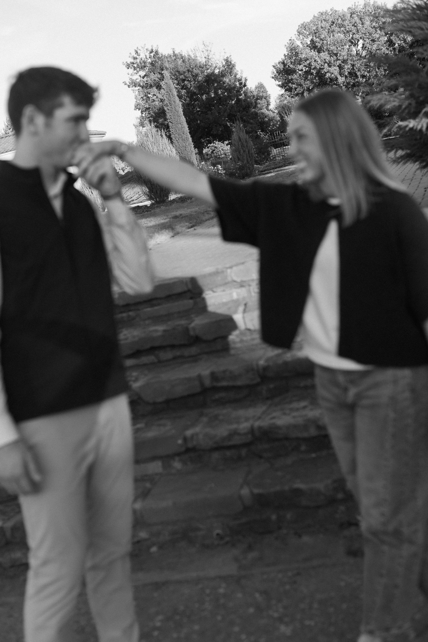 A playful black and white photo of a couple having fun on stone steps outdoors.