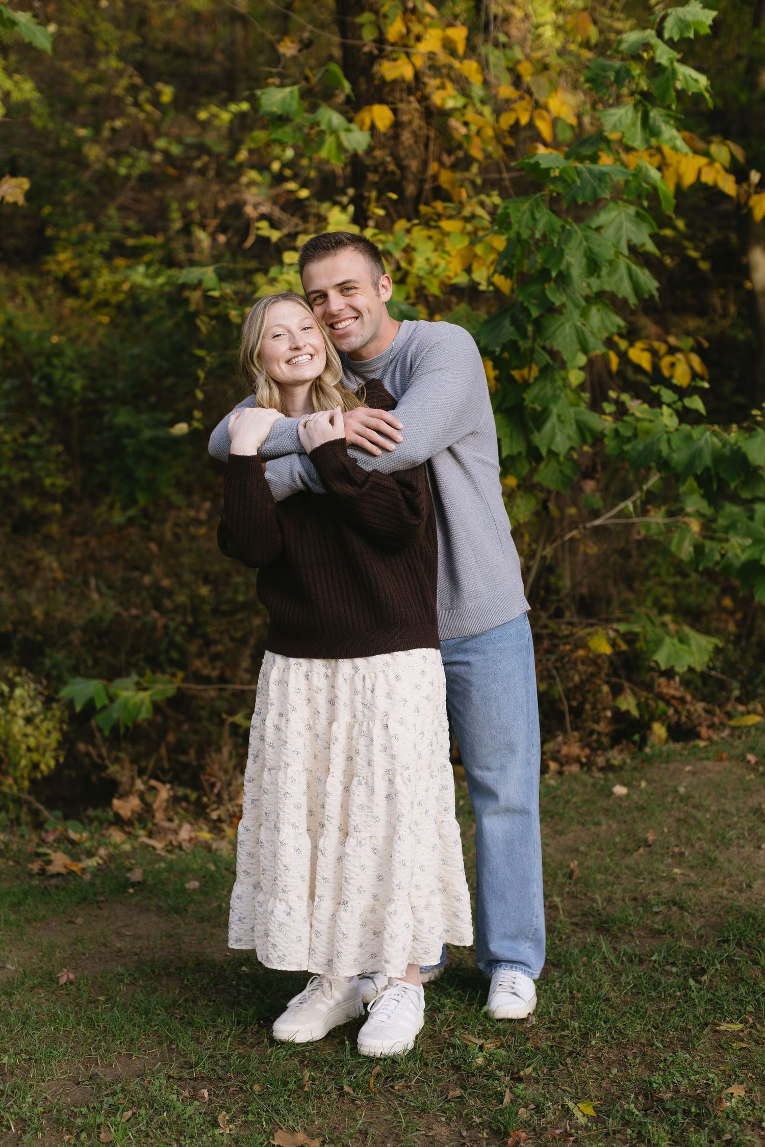 Playful autumn photoshoot of couple in casual wear against fall foliage.