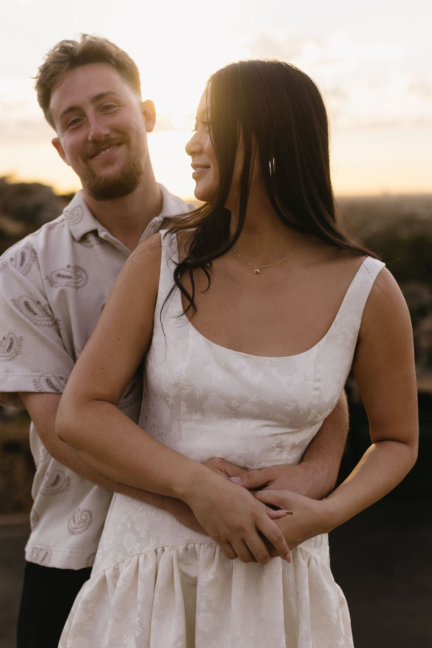 Romantic couple's photoshoot at golden hour with the person in white wearing a sleeveless dress.