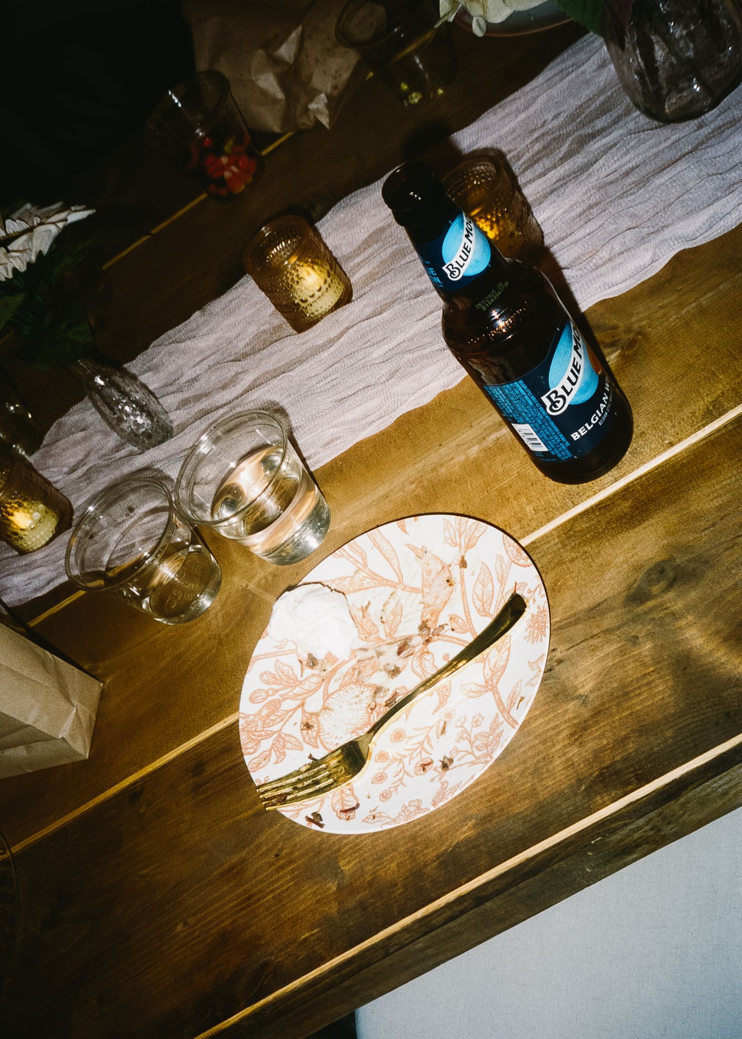 Wooden table with beer bottles and plates at a casual dining setting.