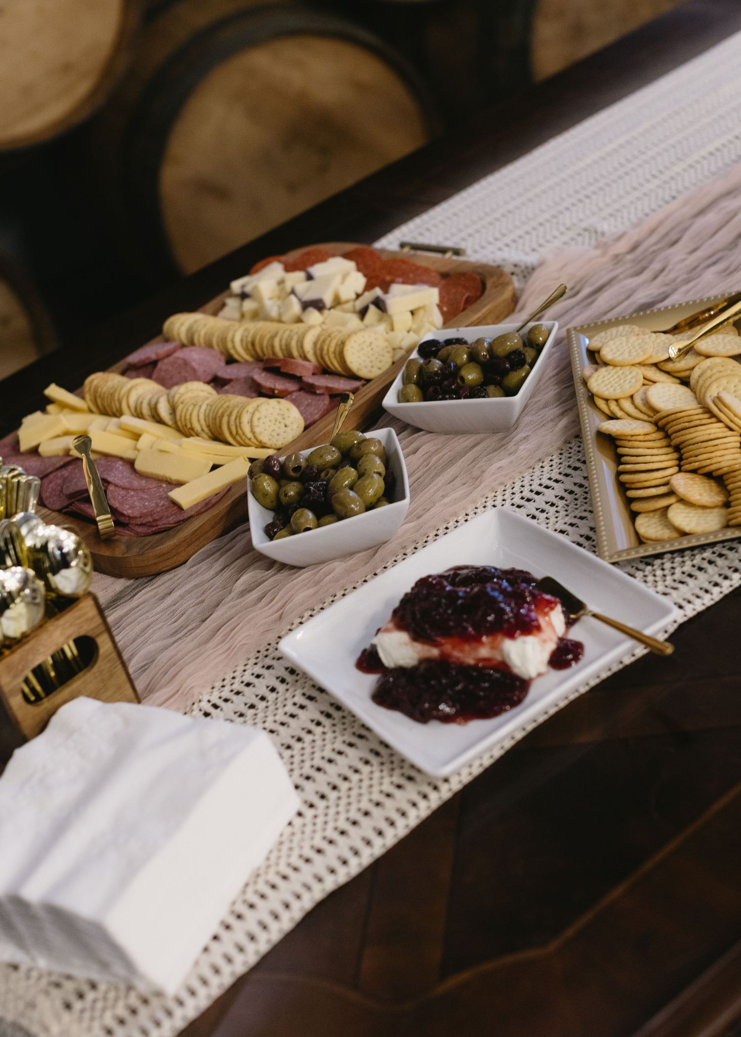 Elegant charcuterie and appetizer spread on a white tablecloth with various meats and crackers.