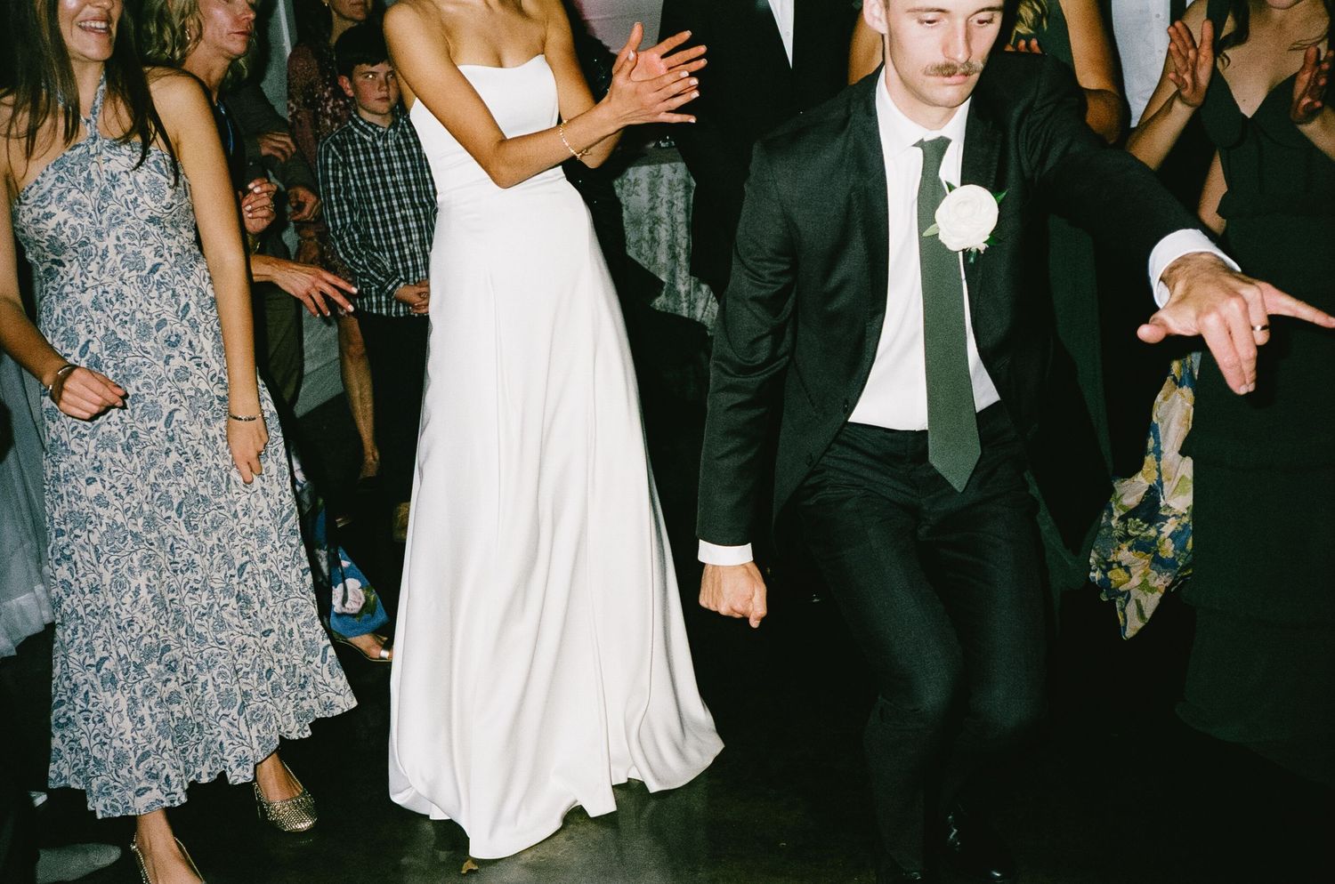 Wedding guests dancing and celebrating at a reception with the newlyweds.