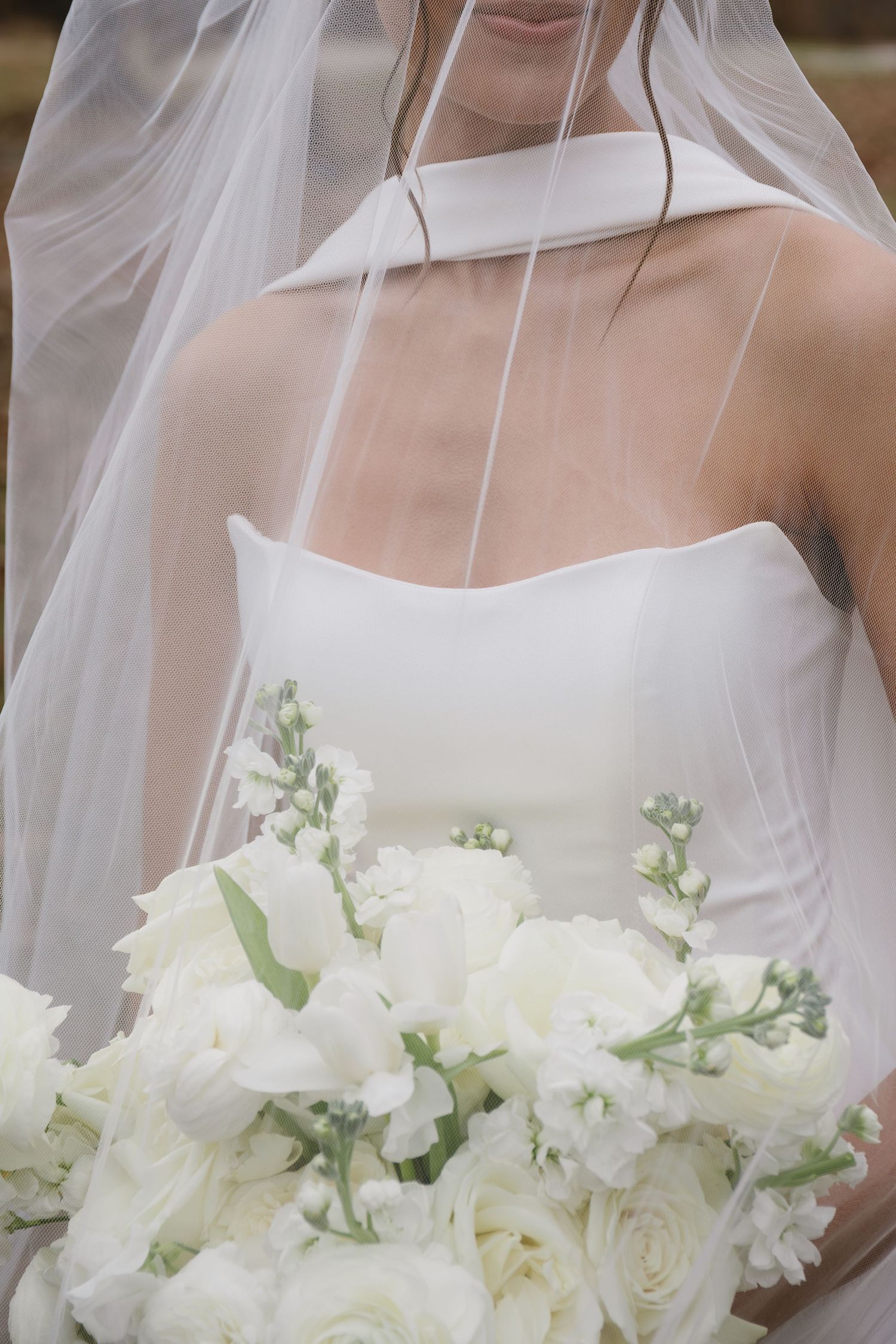 Elegant white bridal bouquet featuring roses and delicate greenery against a light background.