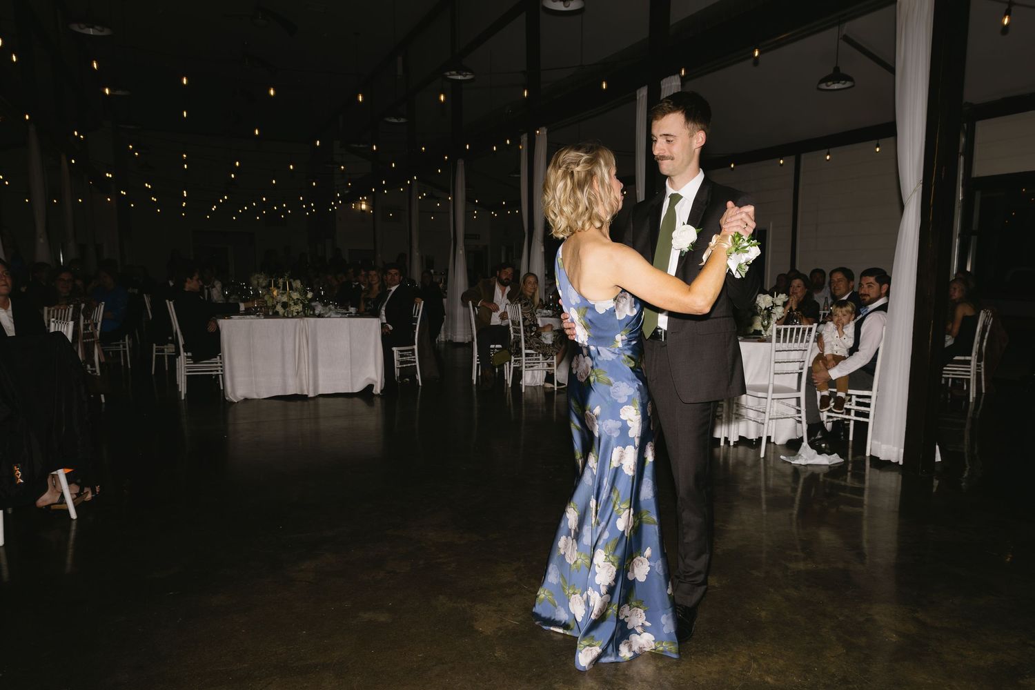 Wedding reception dance floor with guests celebrating under dimmed lighting.