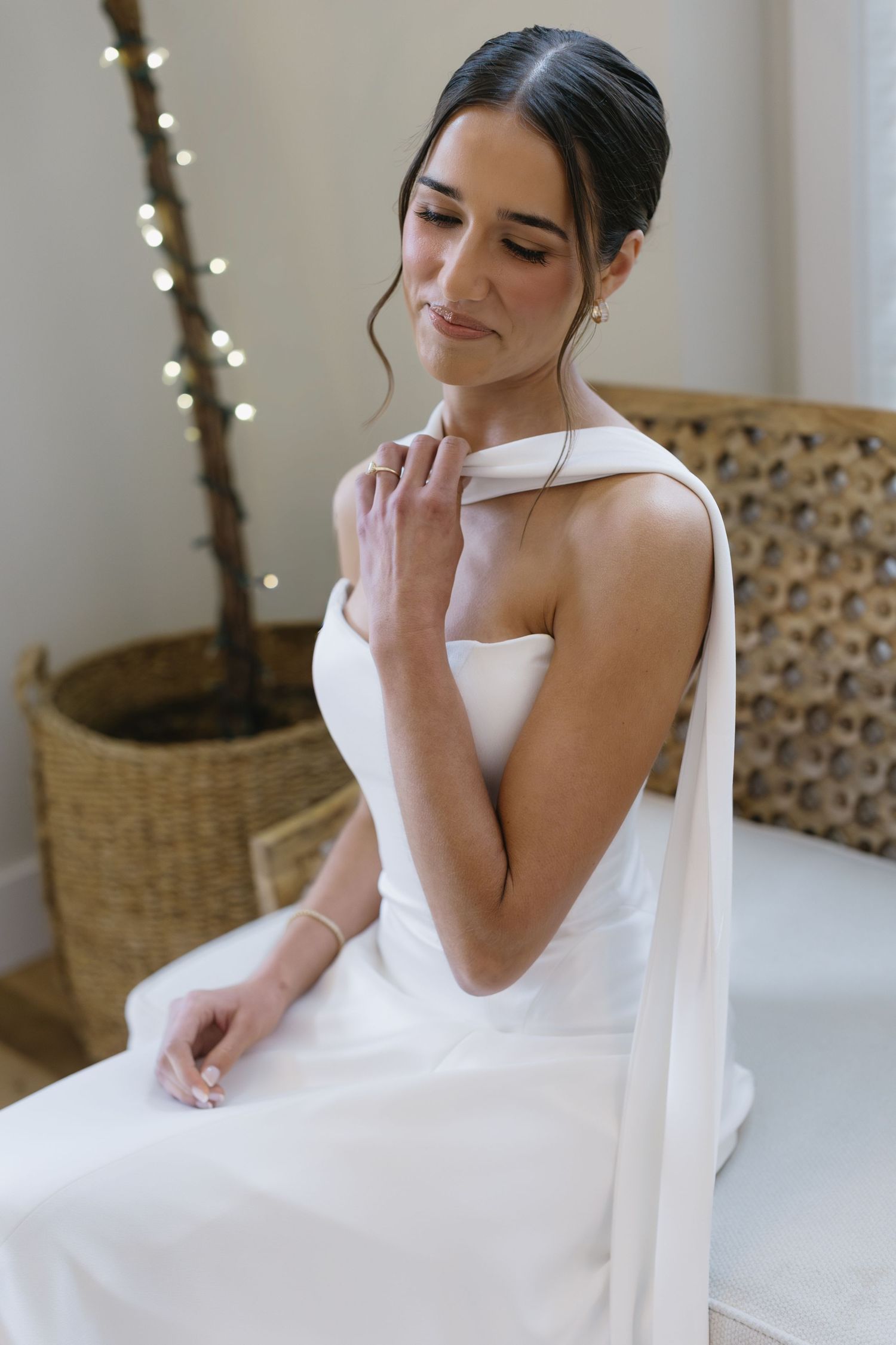 A serene bridal portrait showing a white wedding gown with unique neckline detail and delicate styling.