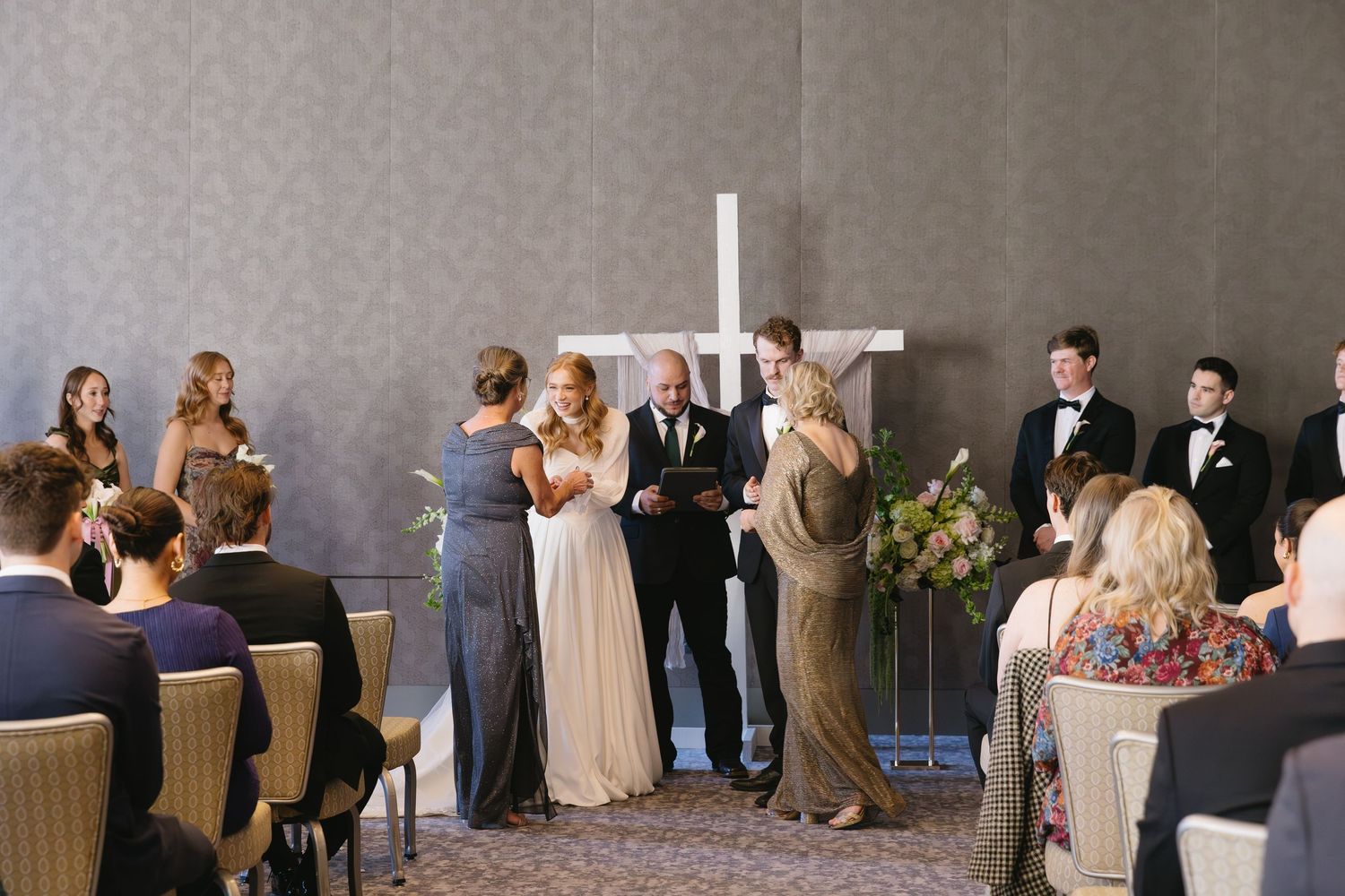 Wedding reception guests seated at decorated tables in elegant venue.