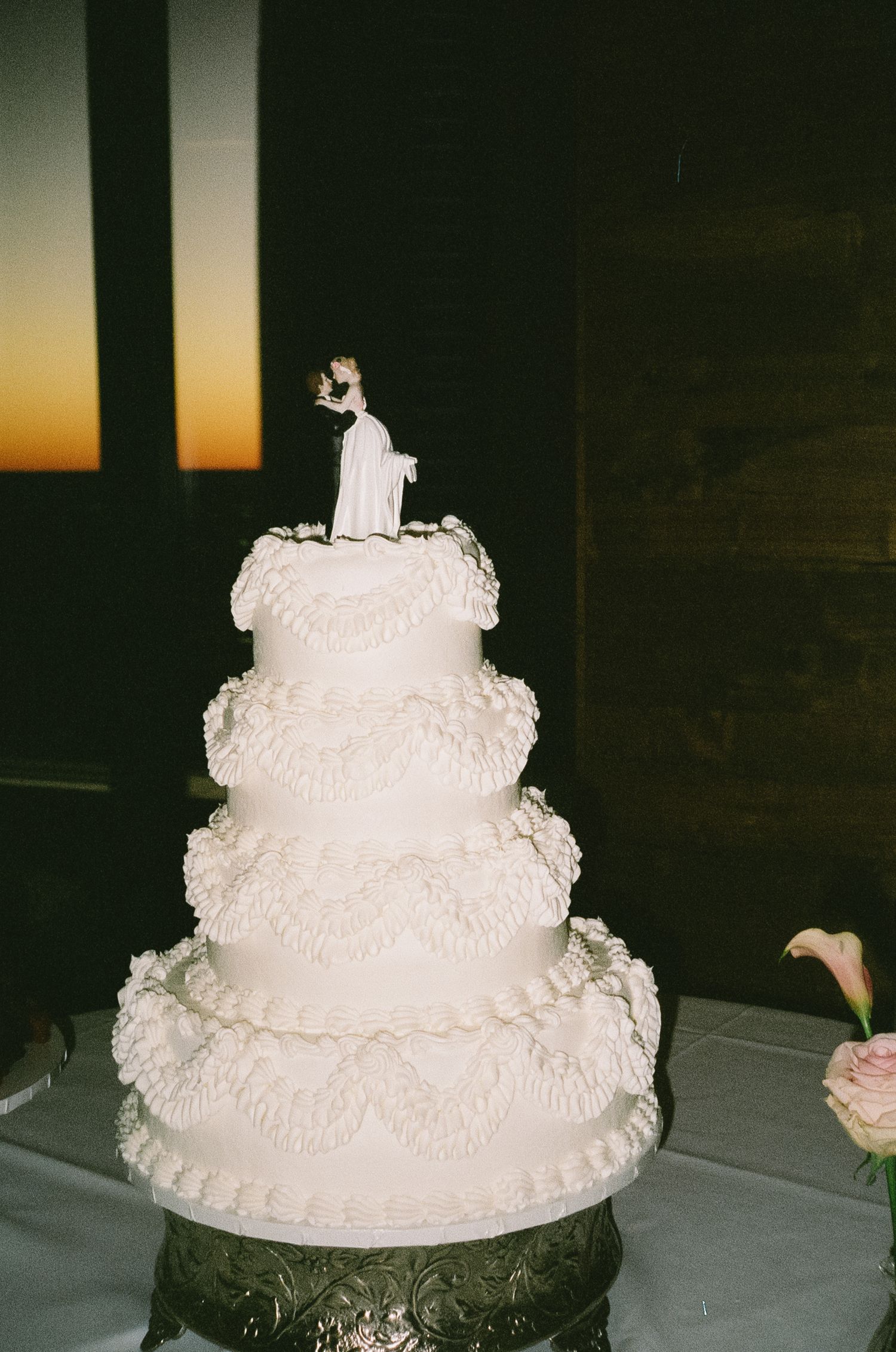Three-tiered white wedding cake with delicate ruffled frosting details.