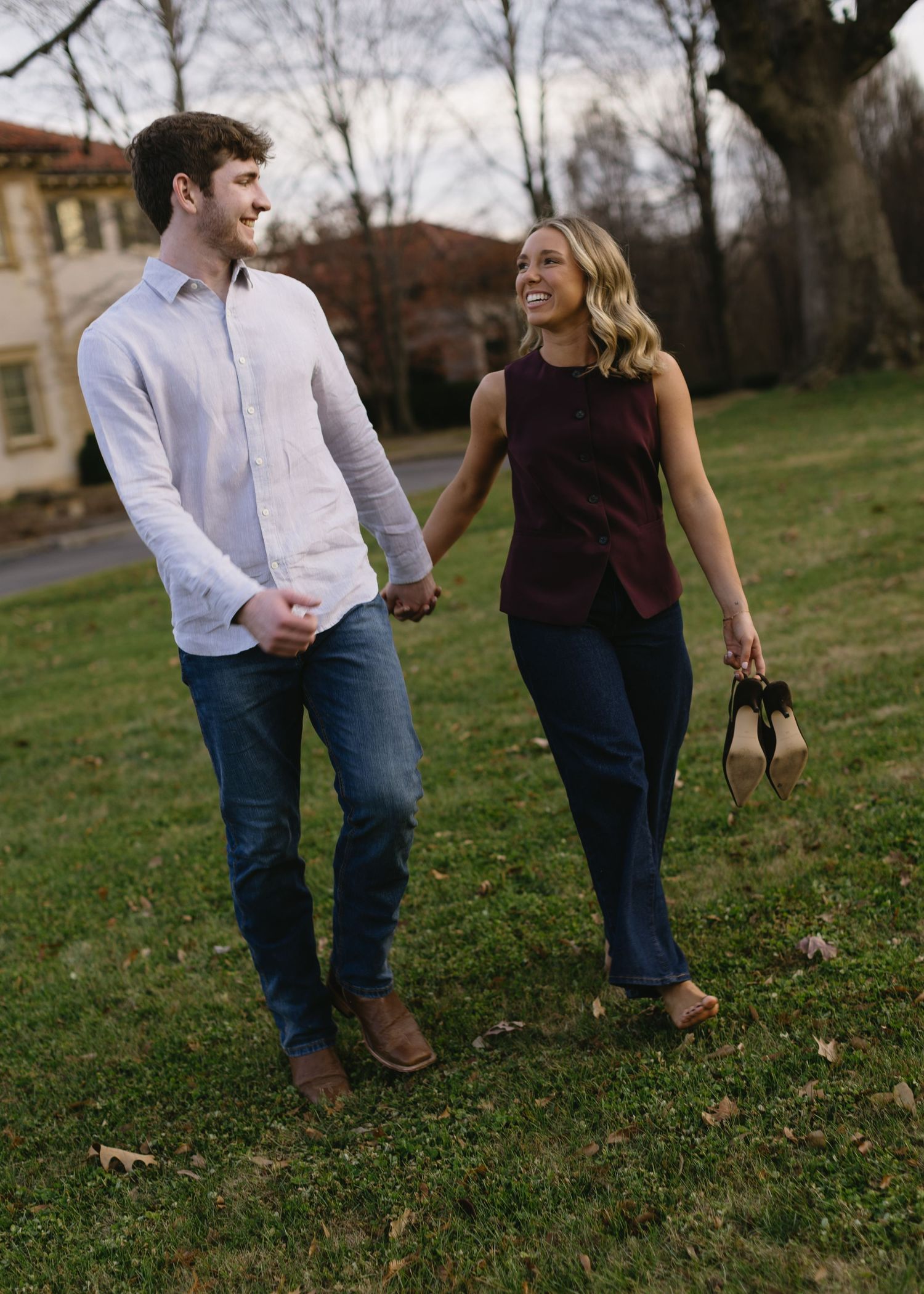 A playful couple walking and laughing together on grass during an autumn day.