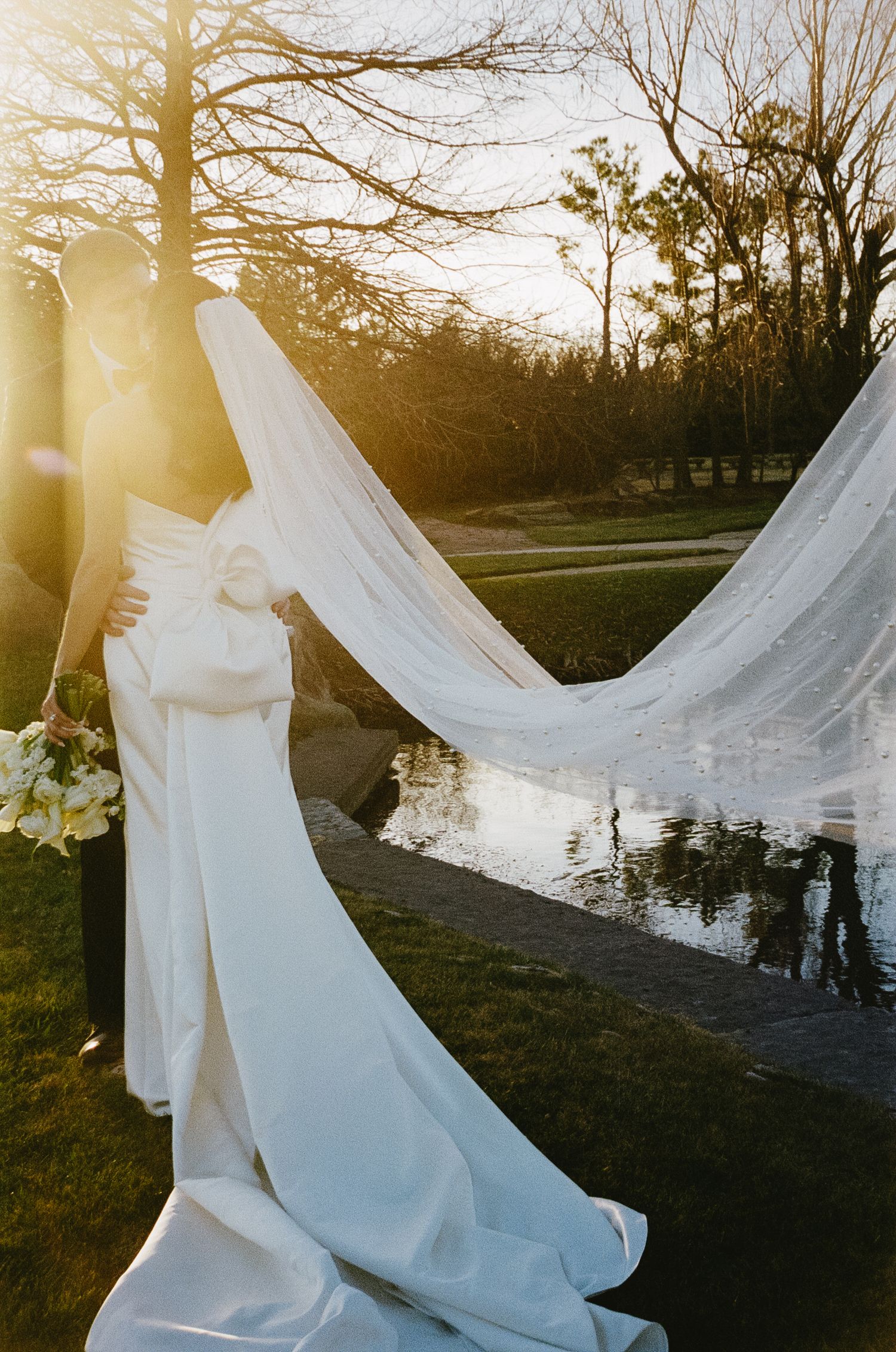 Flowing white wedding dress veil billowing in the wind during golden hour.
