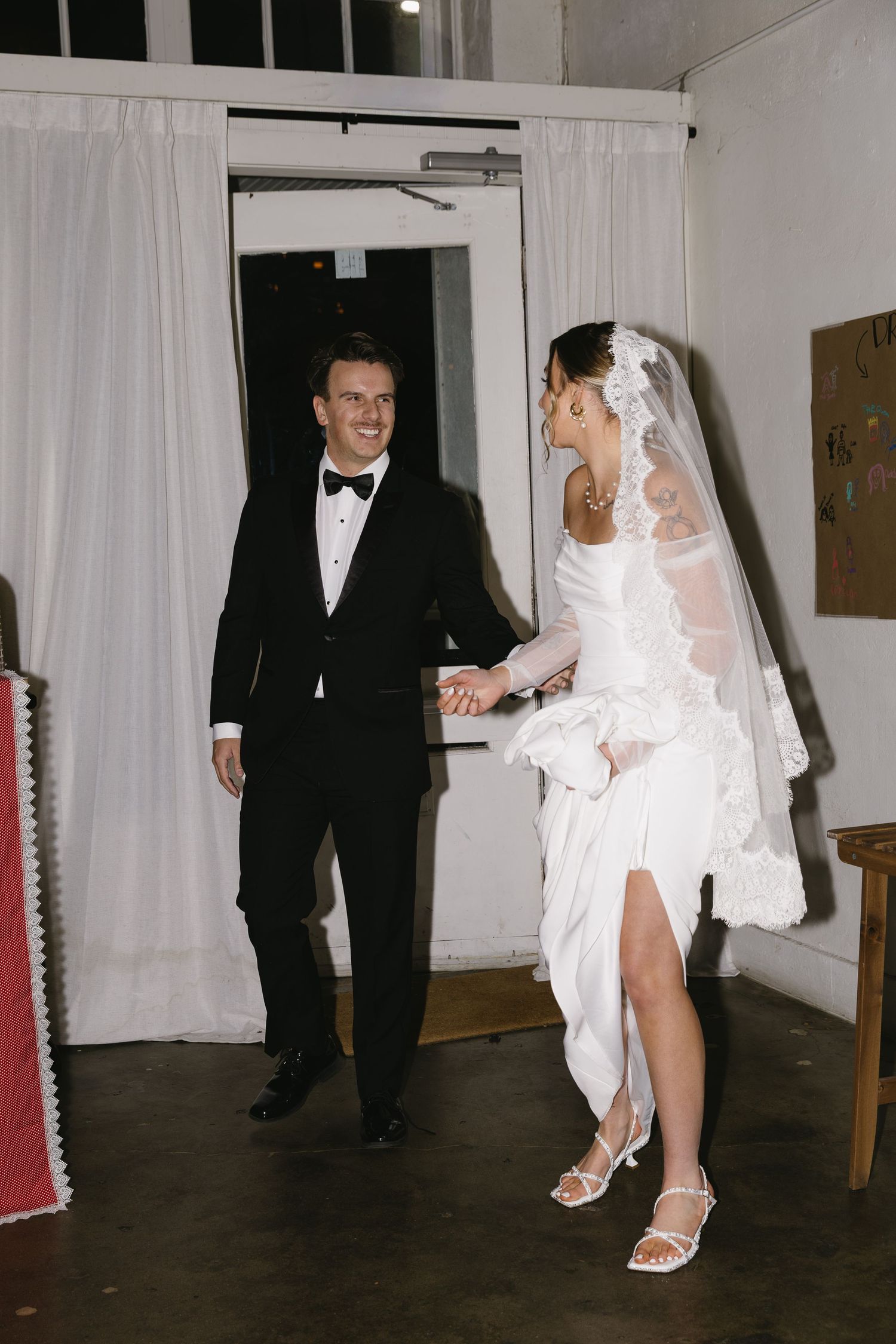 Wedding couple sharing playful moments while walking through a venue hallway.