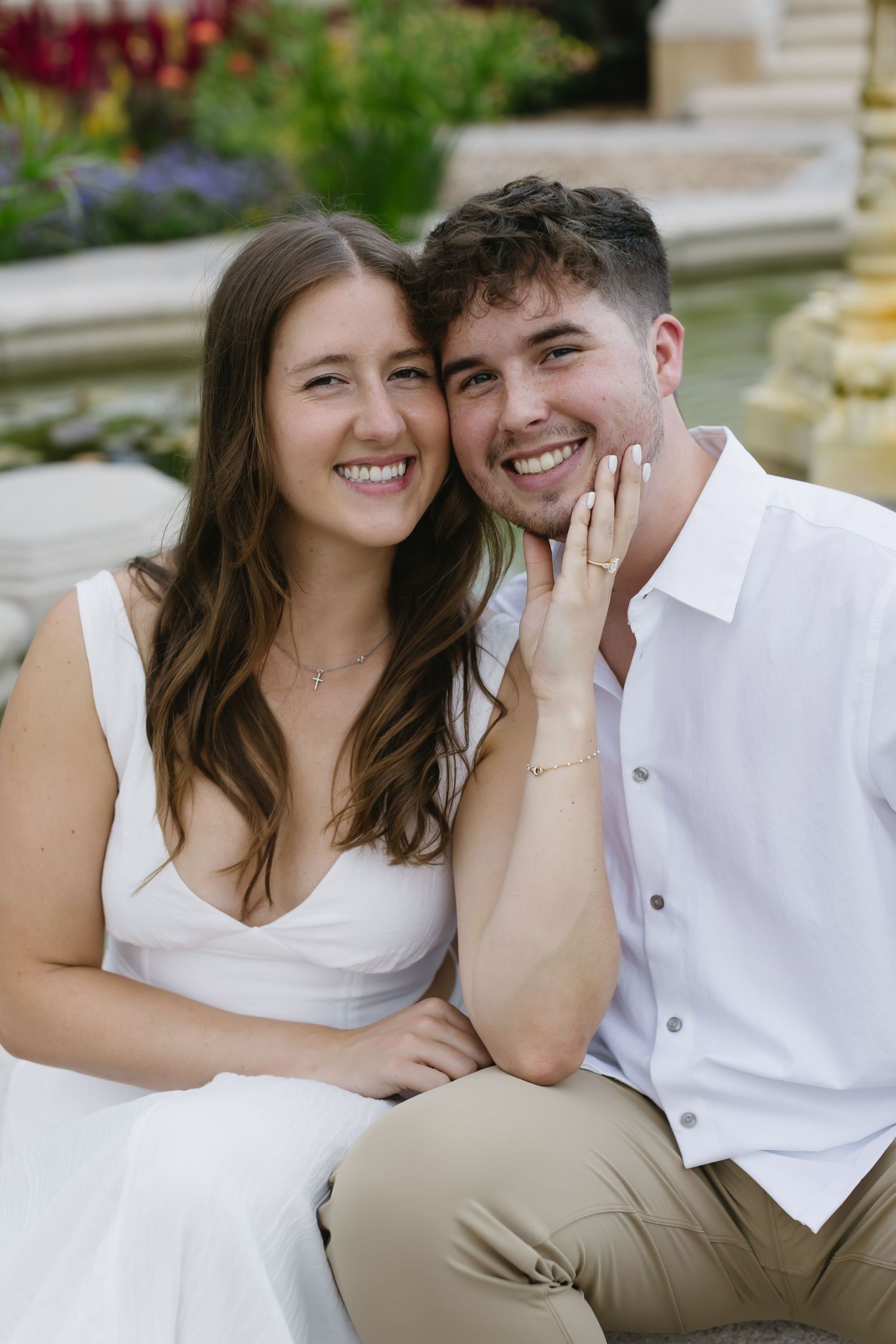 A couple in white and khaki outfits shares joyful moments together on a bench.