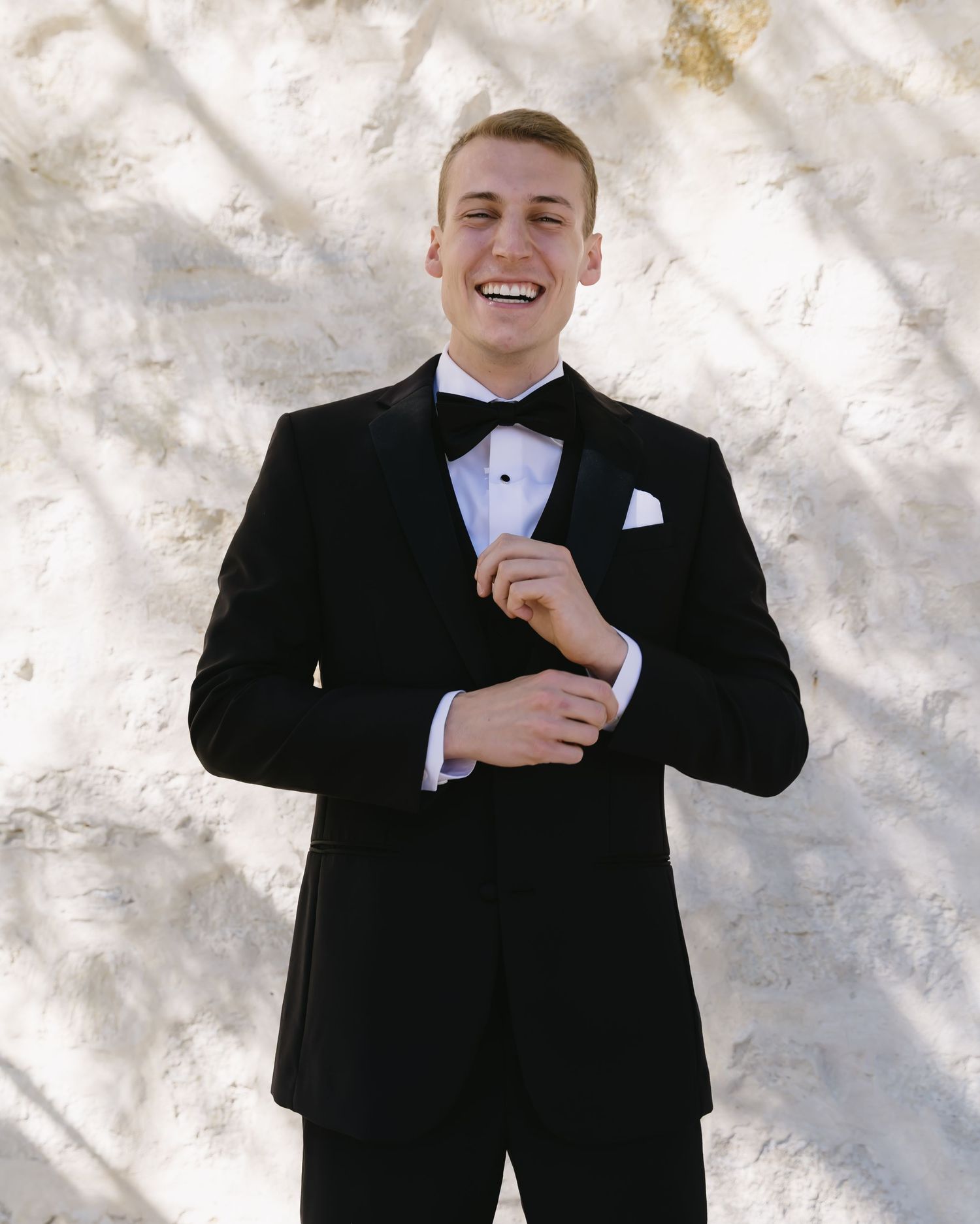 Groom in classic black tuxedo adjusting his tie in sequence of candid shots.