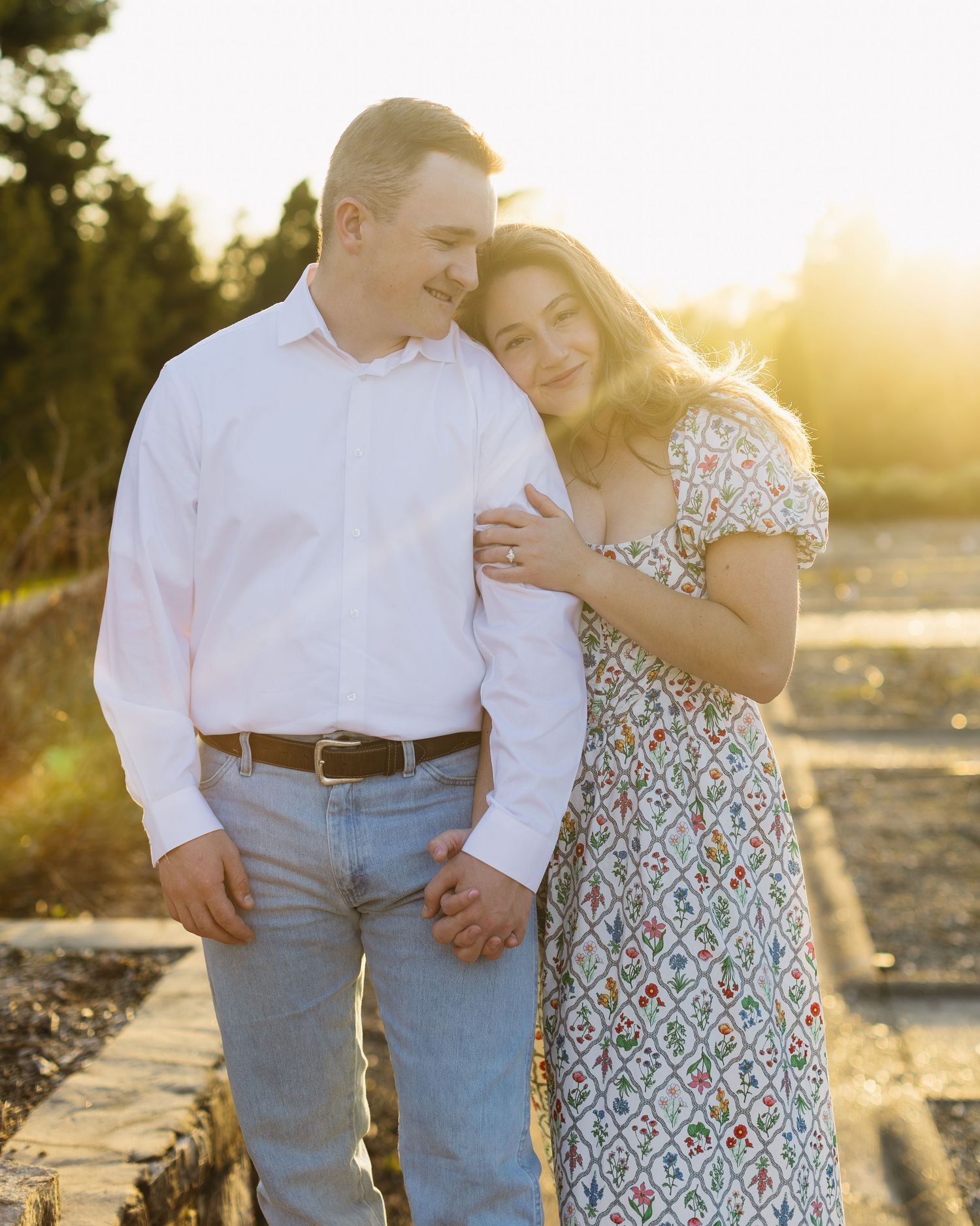 Romantic sunset photoshoot with couple in coordinated white and floral outfits.
