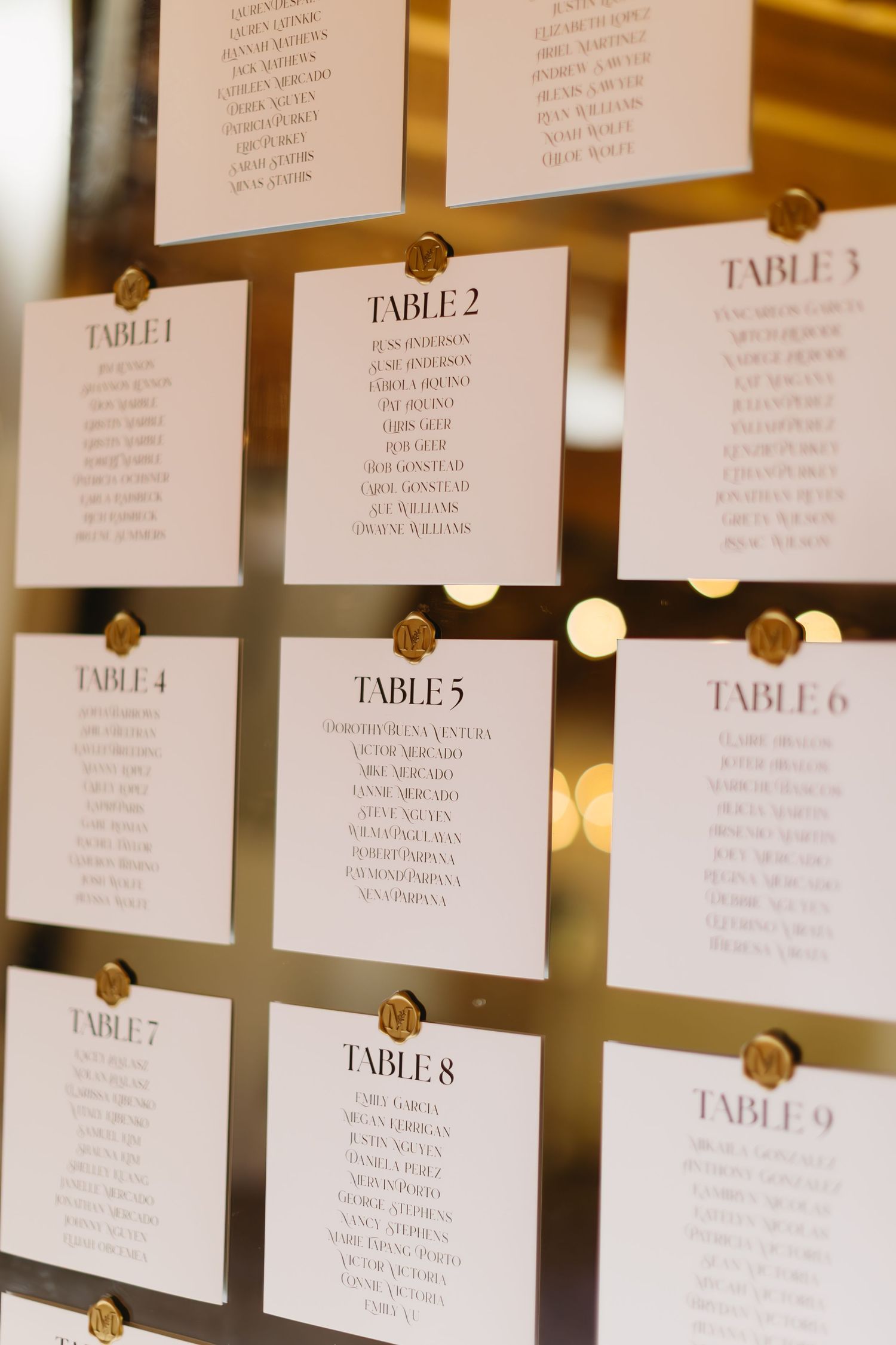 Wedding seating chart display with table numbers and guest names arranged on a wall.