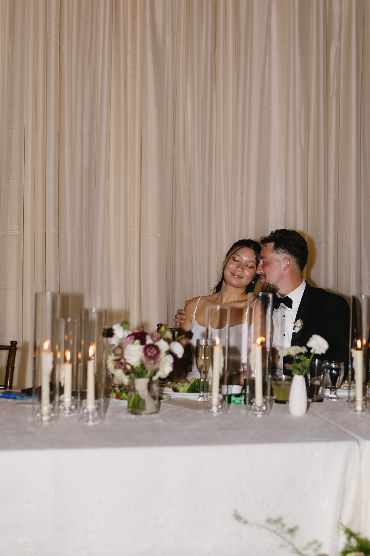 Romantic candlelit wedding reception table with couple sharing an intimate moment.