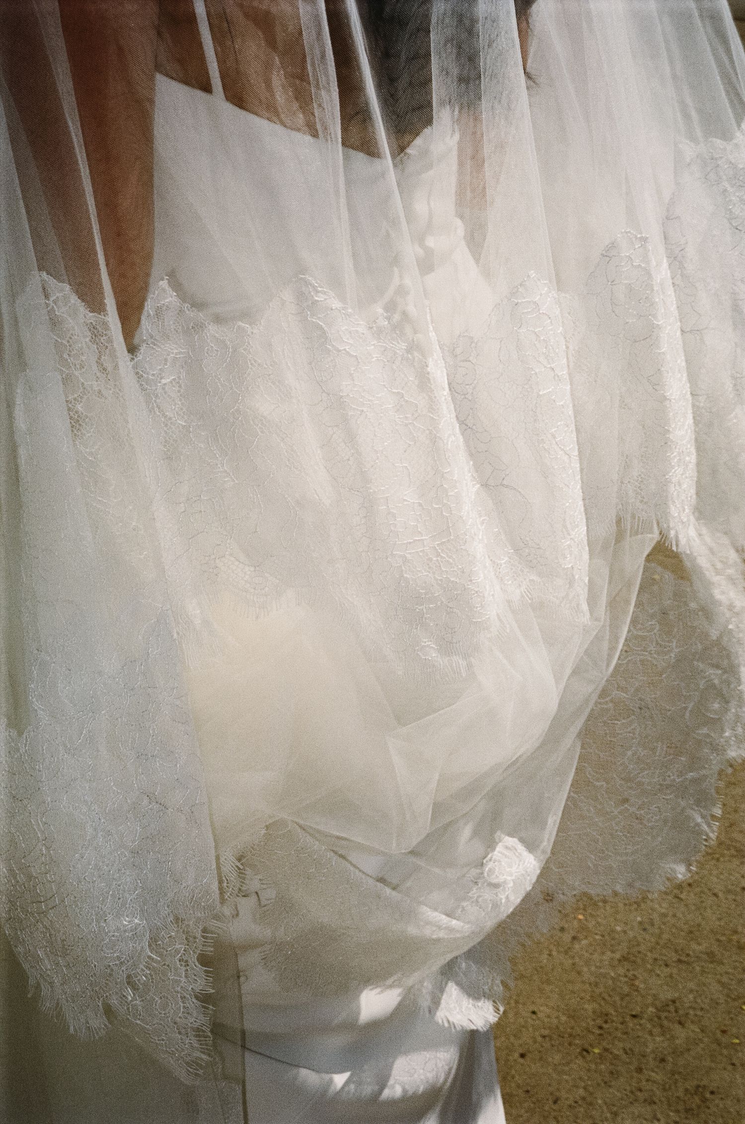Close-up details of a flowing white wedding dress with delicate lace and tulle fabric.