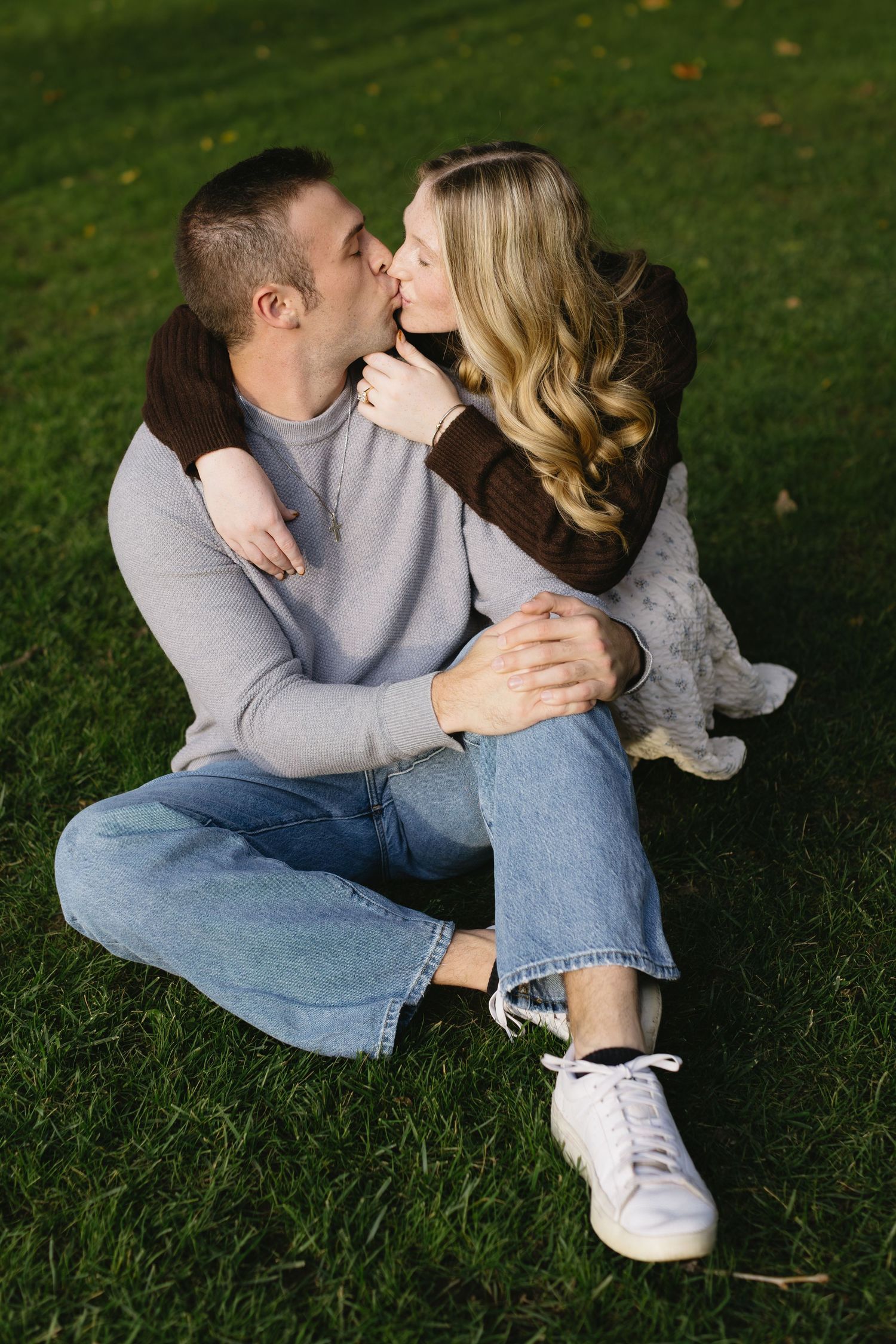 Couple shares tender moments while sitting together on green grass.