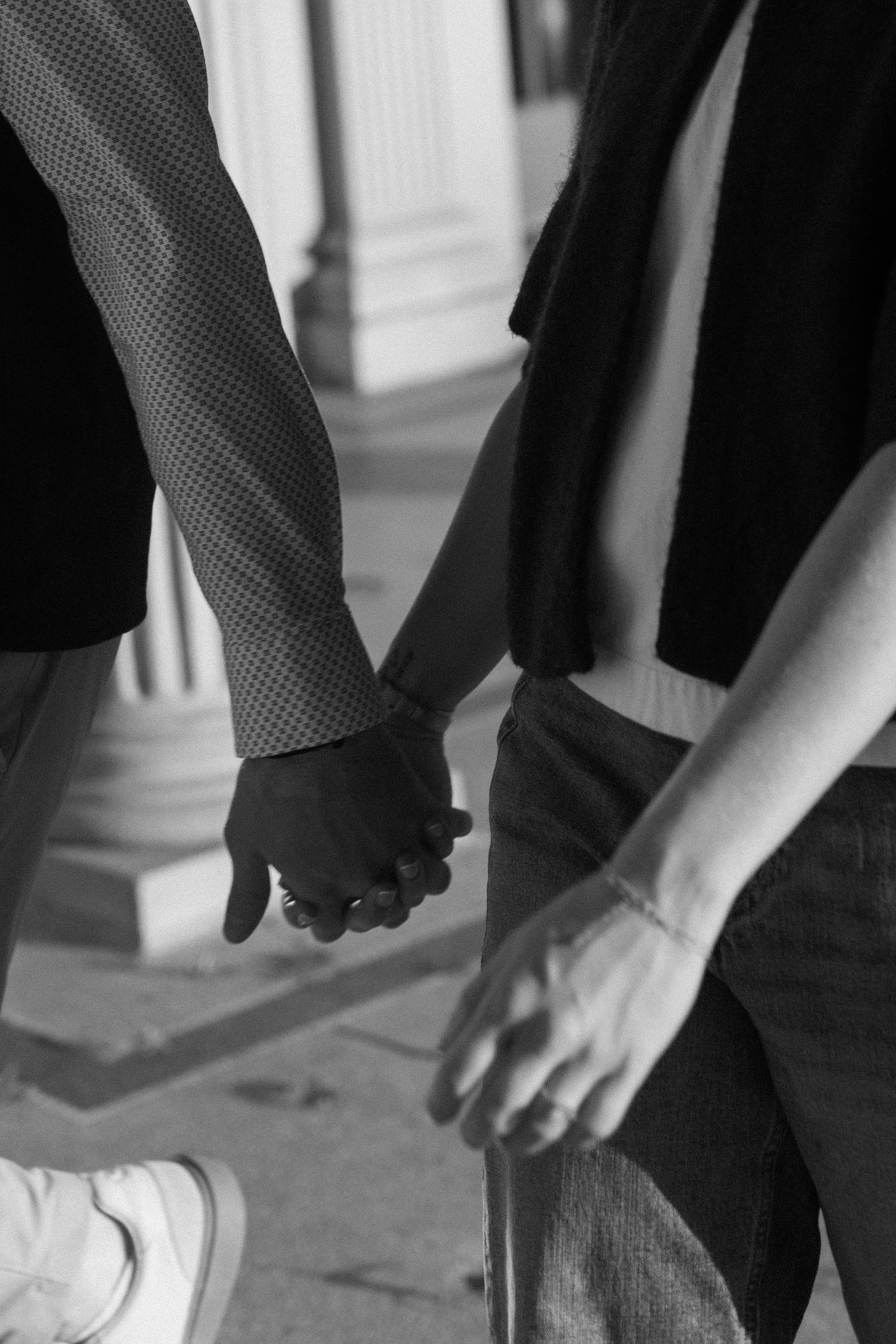 Low angle shot of hands reaching toward each other against architectural backdrop.