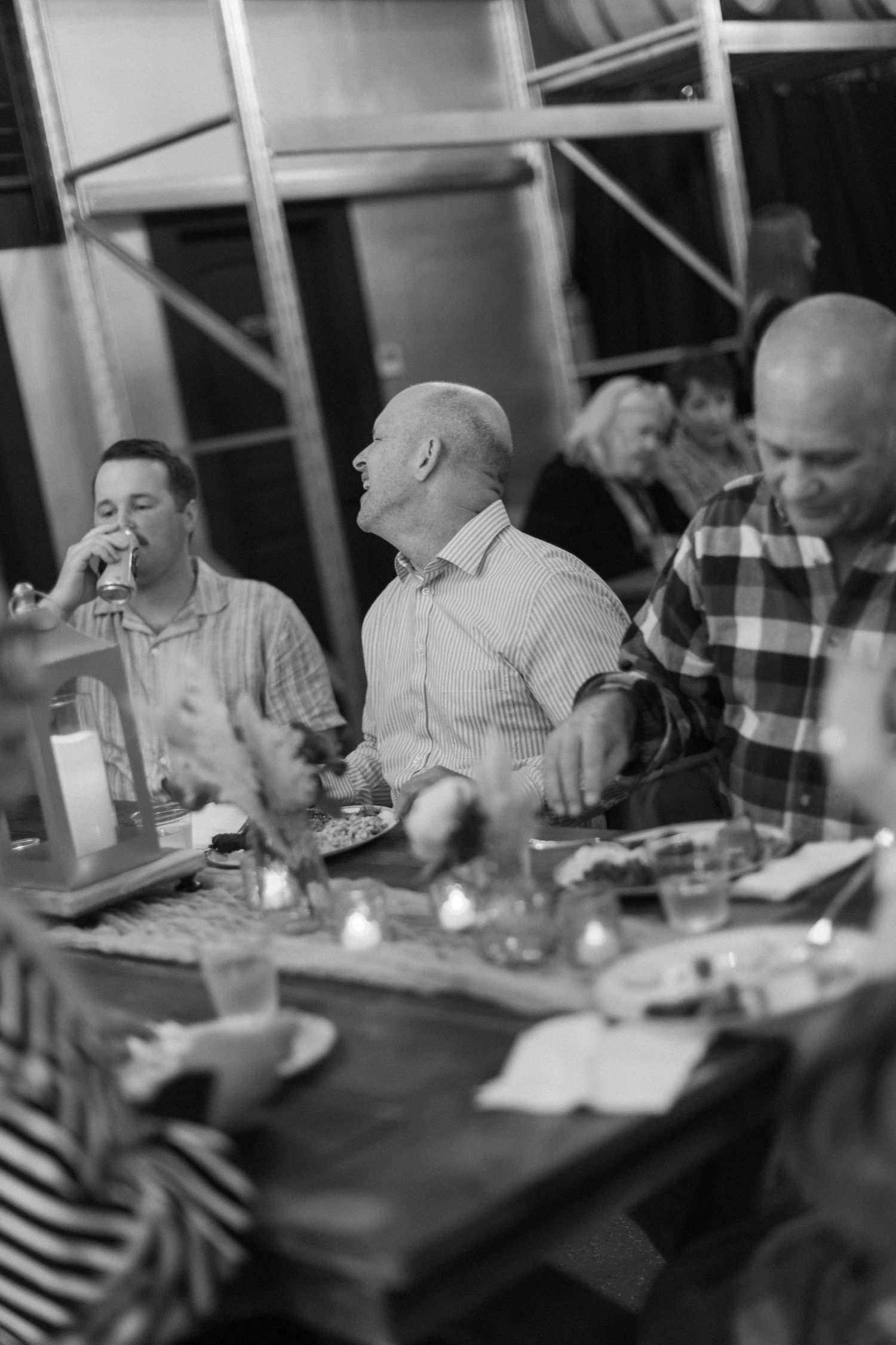 Group dining at a long table enjoying a meal in black and white photography.