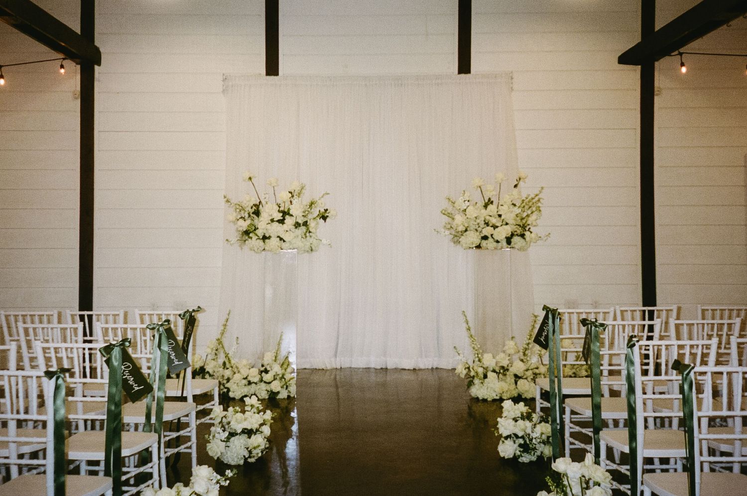 Modern wedding ceremony space with white chairs and floral arrangements.