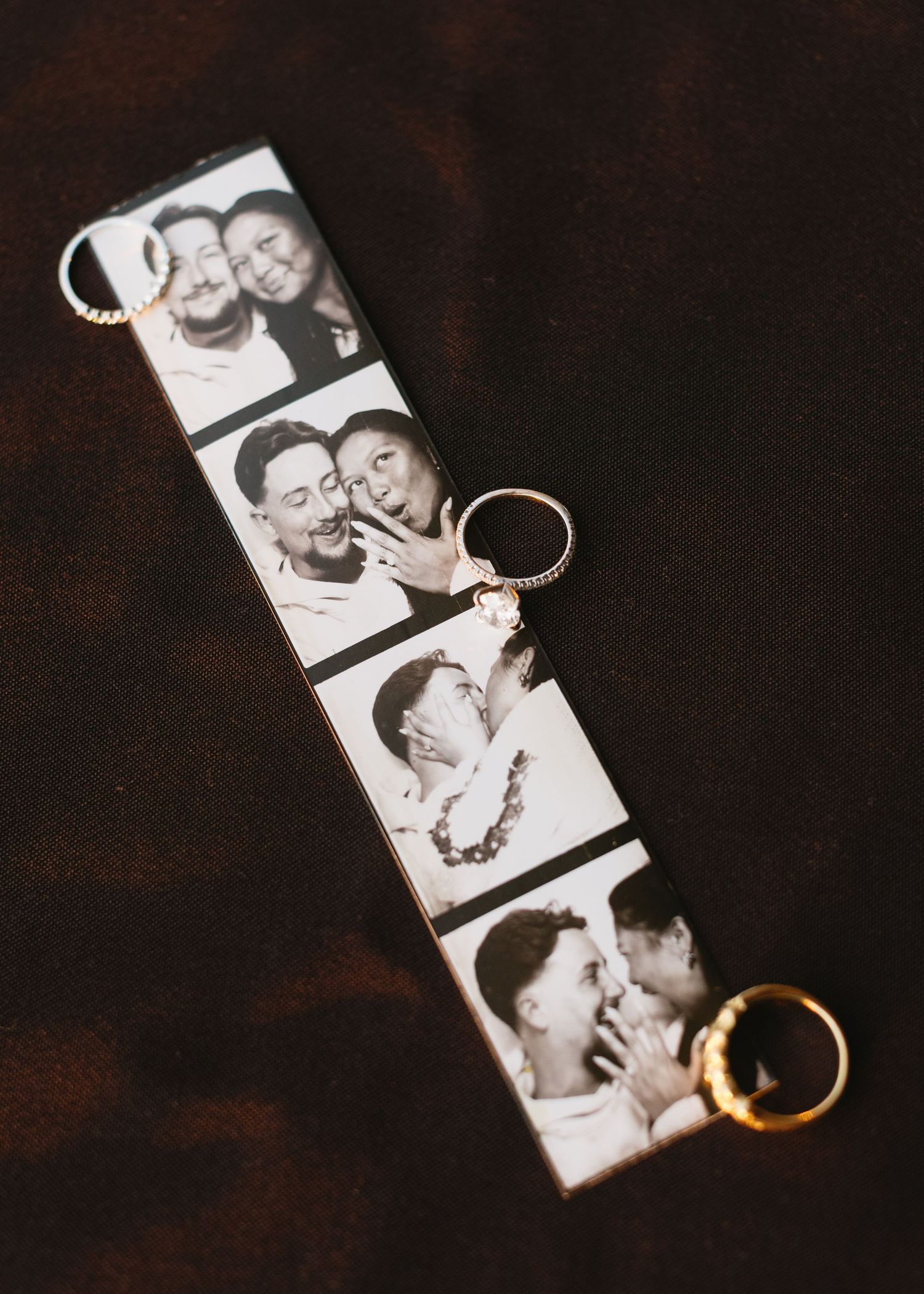 Wedding rings rest on black and white photo strips in artistic composition.