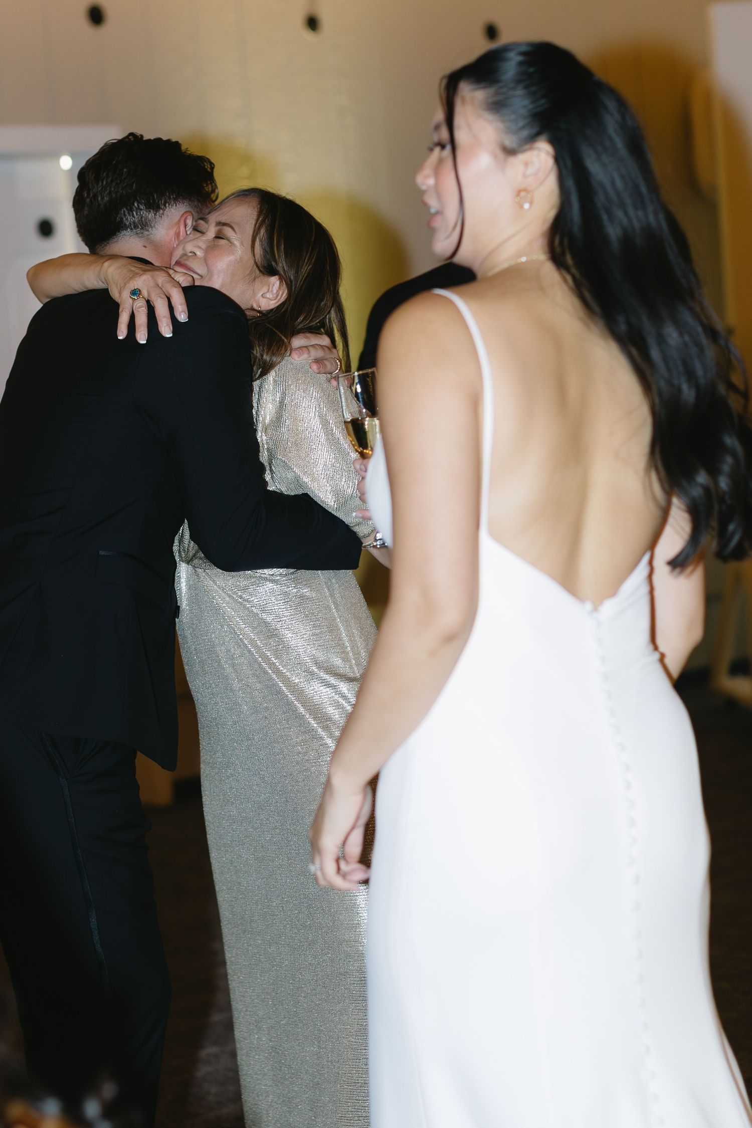 Wedding reception guests dancing in formal attire under warm indoor lighting.