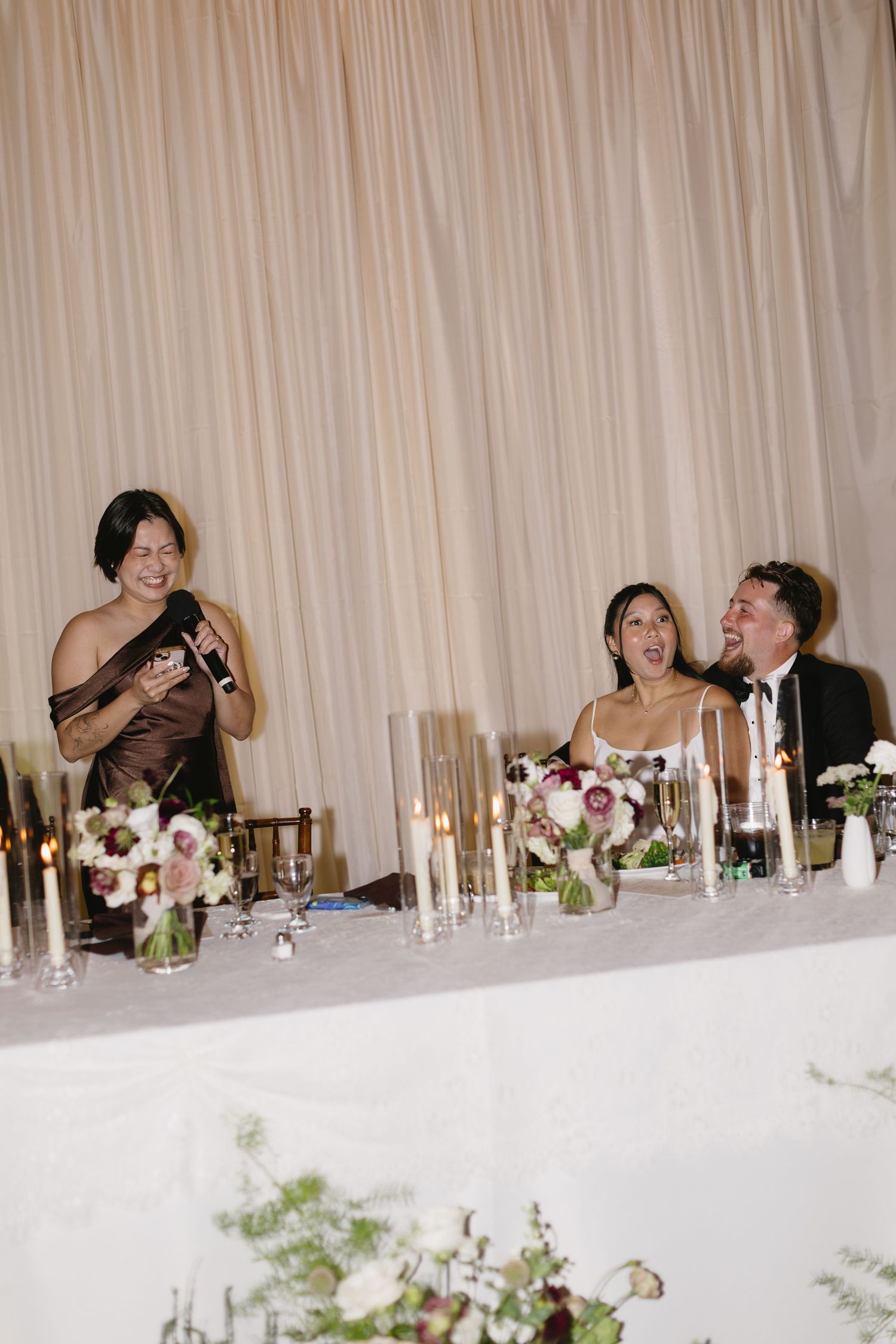 Reception table decorated with candles and flowers as guests celebrate.