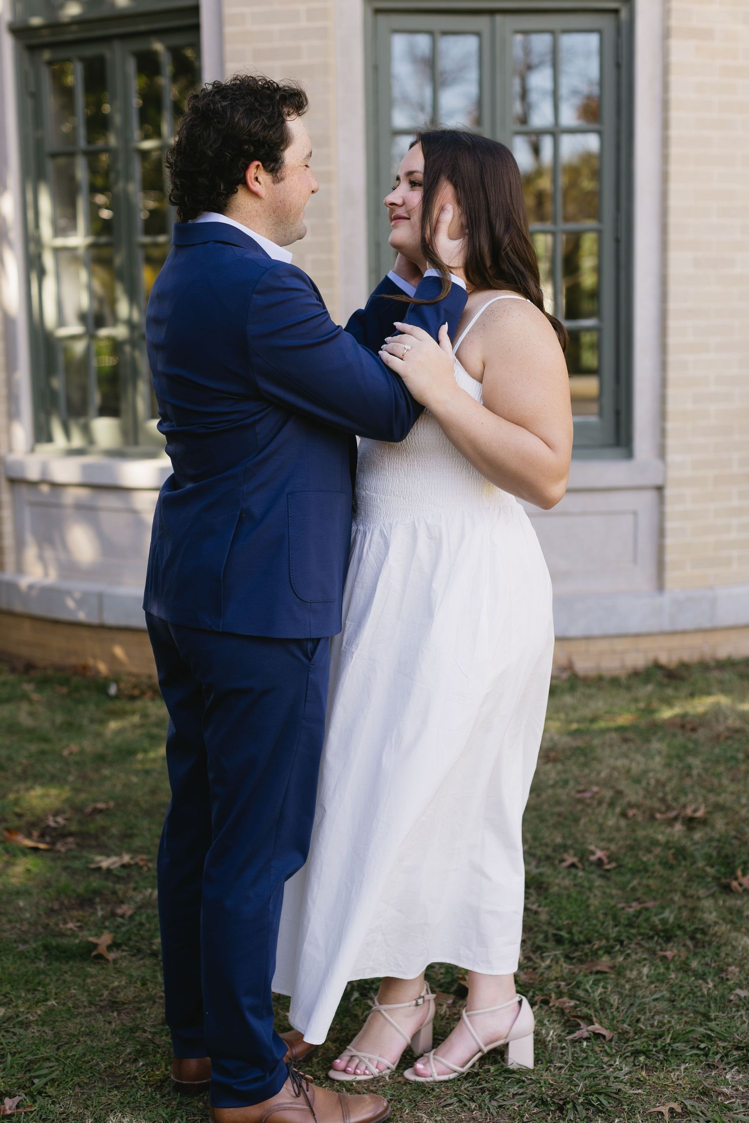 A couple in formal attire share an intimate dance moment outdoors, with the person in blue embracing their partner in white.
