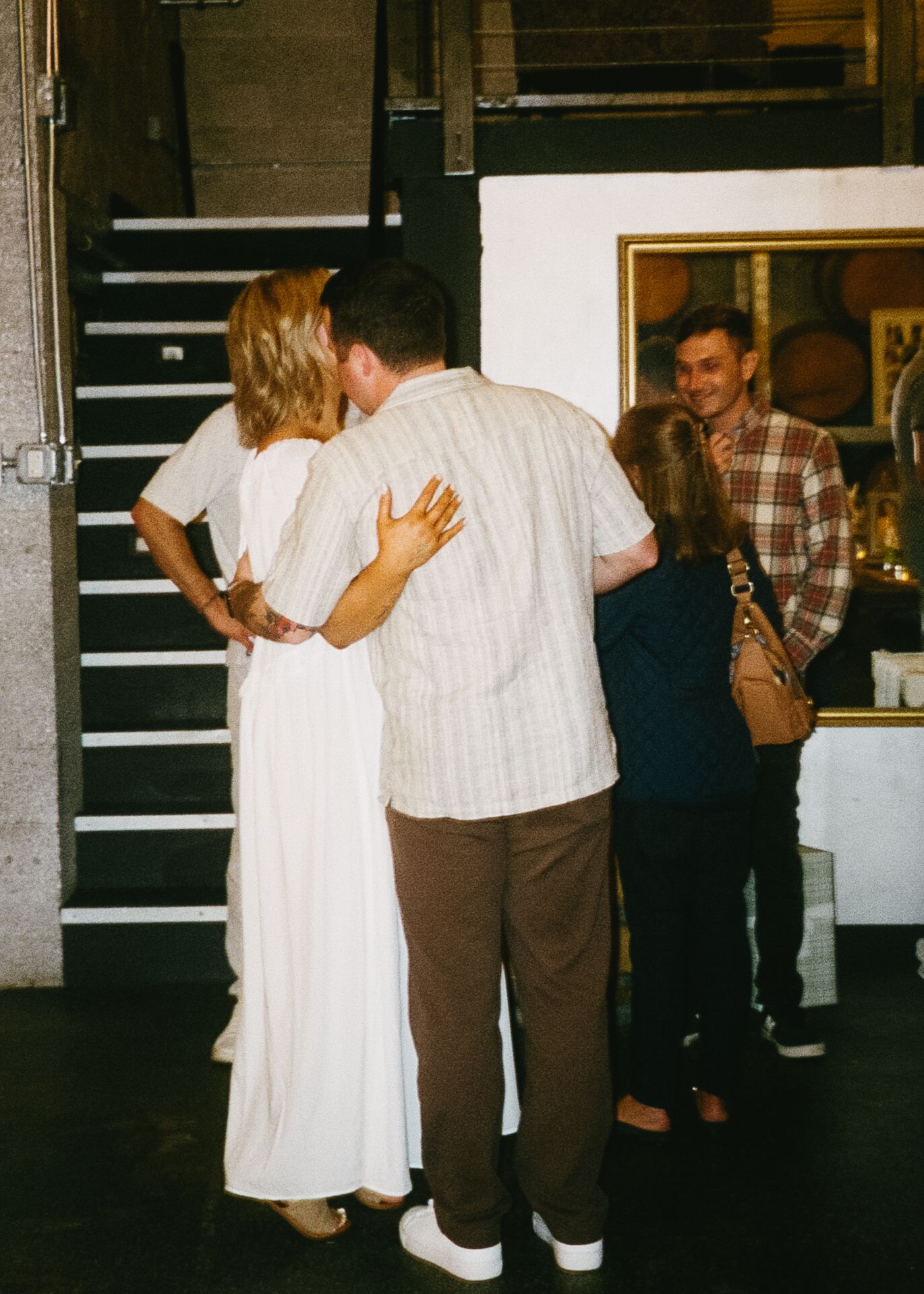 Wedding guests dancing together in formal attire at an indoor reception venue.