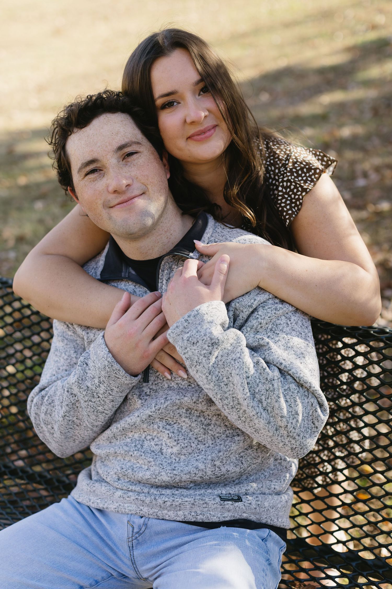 A couple shares tender moments while sitting together on a bench during an autumn photoshoot.