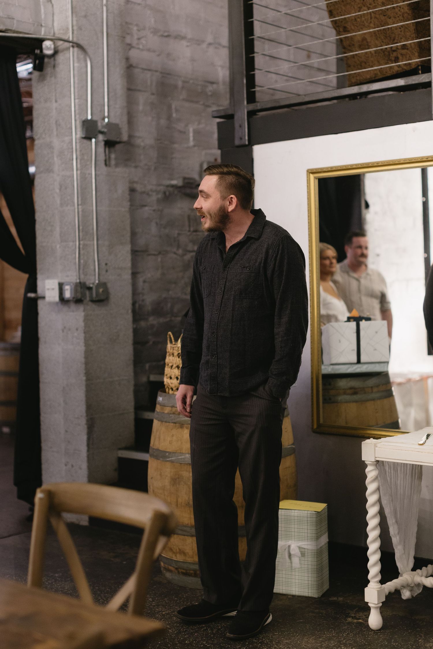 Person in black attire standing in an industrial-style venue with exposed brick walls.