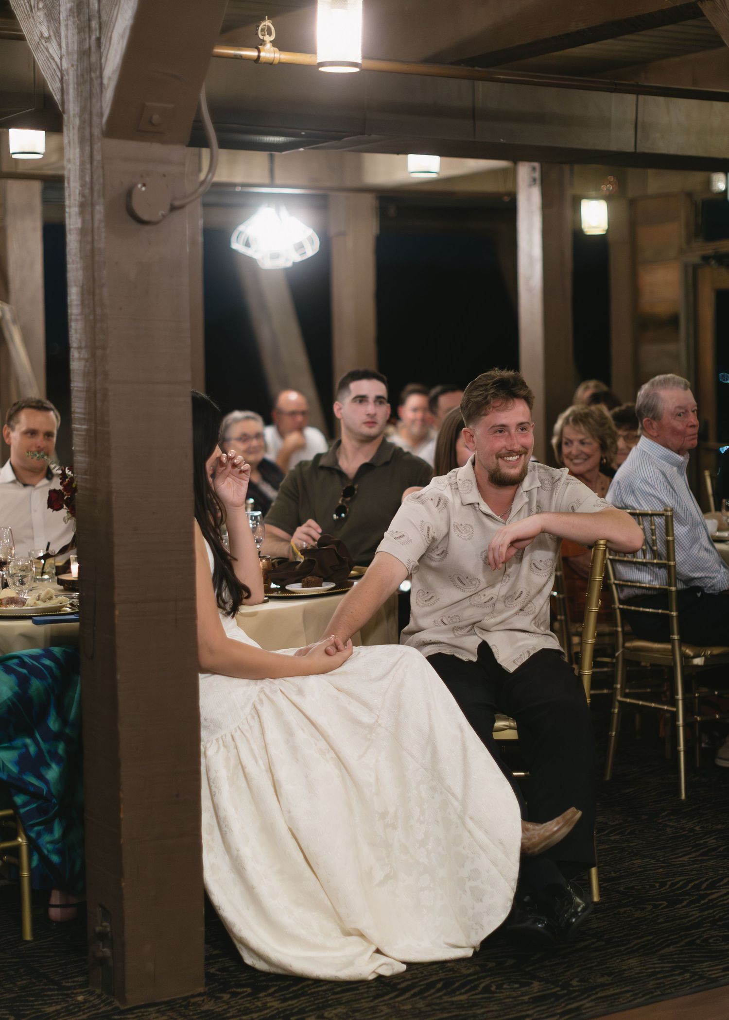 Wedding reception scene in dimly lit venue with white dress in foreground.